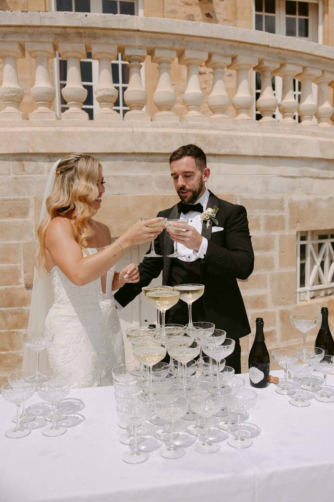 Bride and groom champagne tower toast at classical stone building