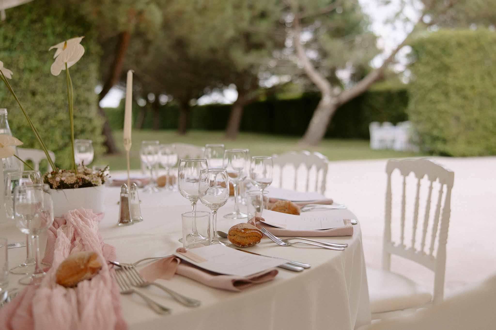 Wedding reception table setting with white ceramic centerpieces in manicured garden