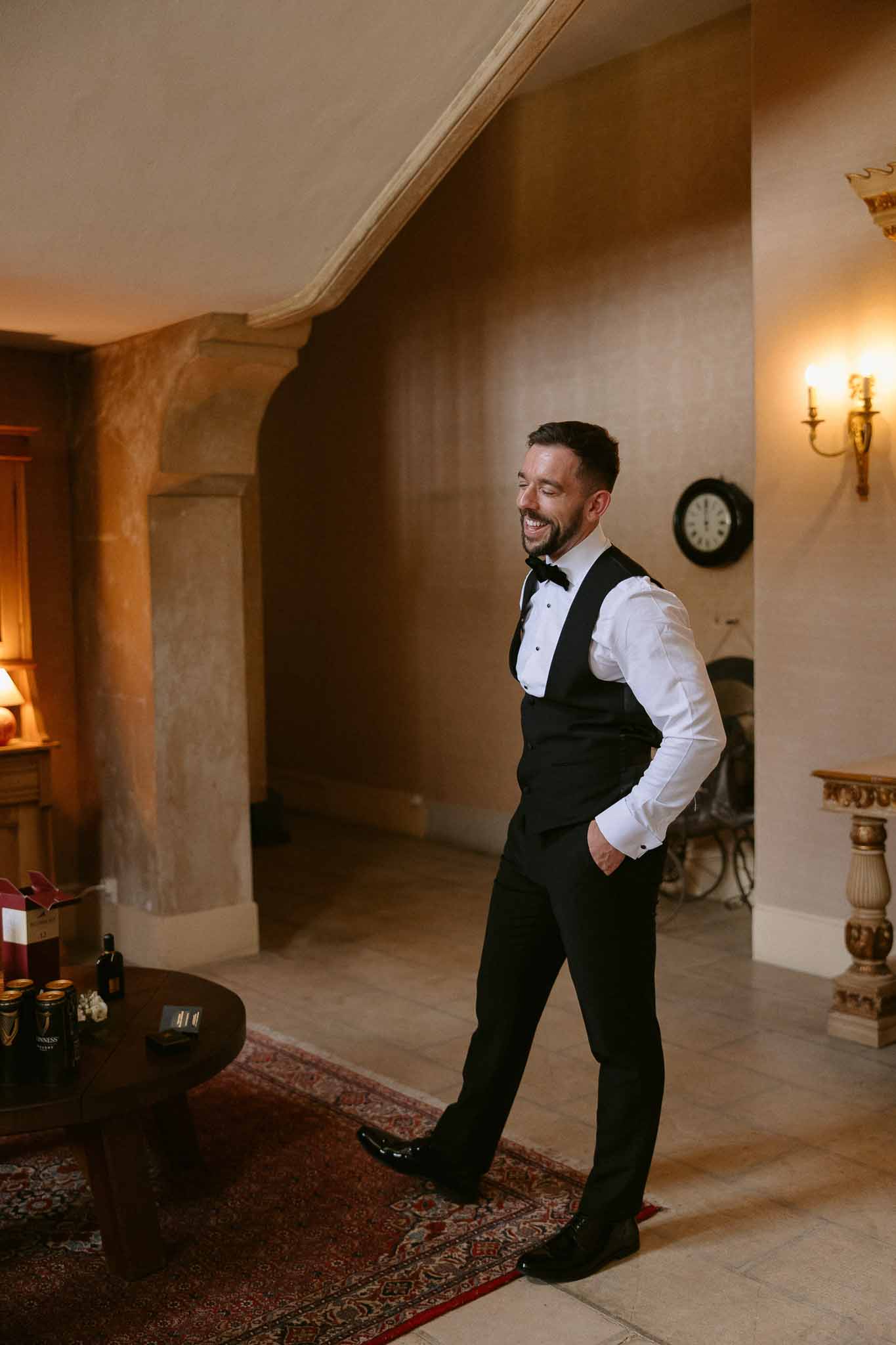 Groom in black tuxedo portrait inside elegant classical venue with ornate architectural details