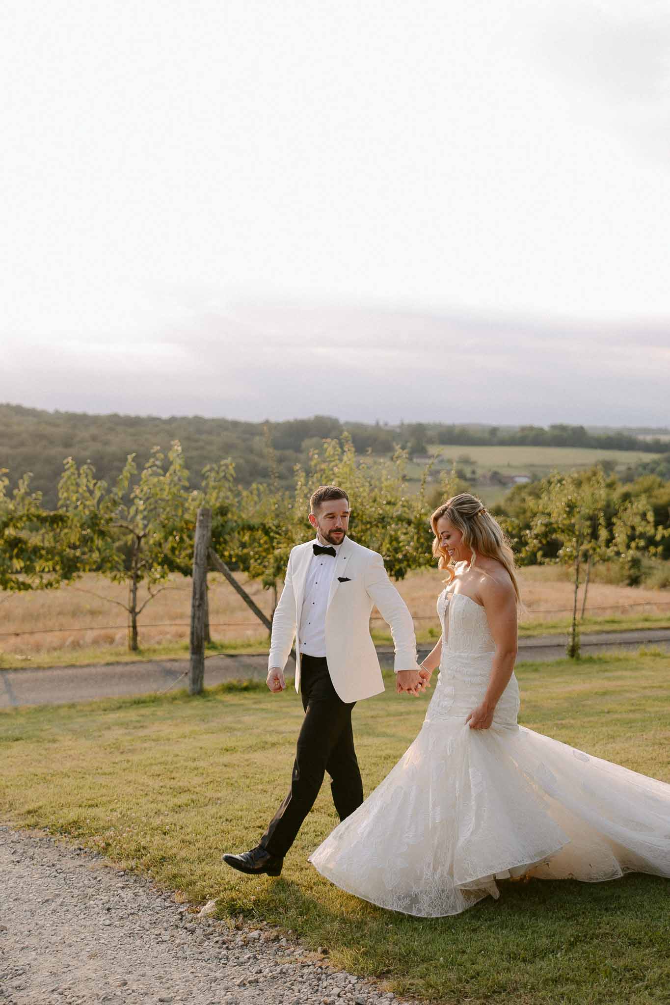 Bride and groom walking hand-in-hand through vineyard rows during portrait session