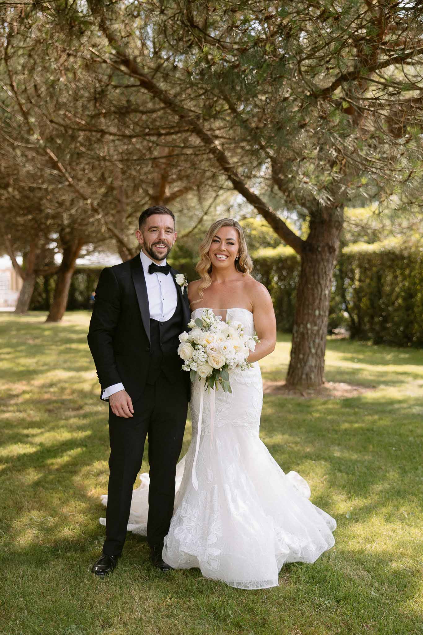 Bride and groom formal portrait under trees on estate grounds