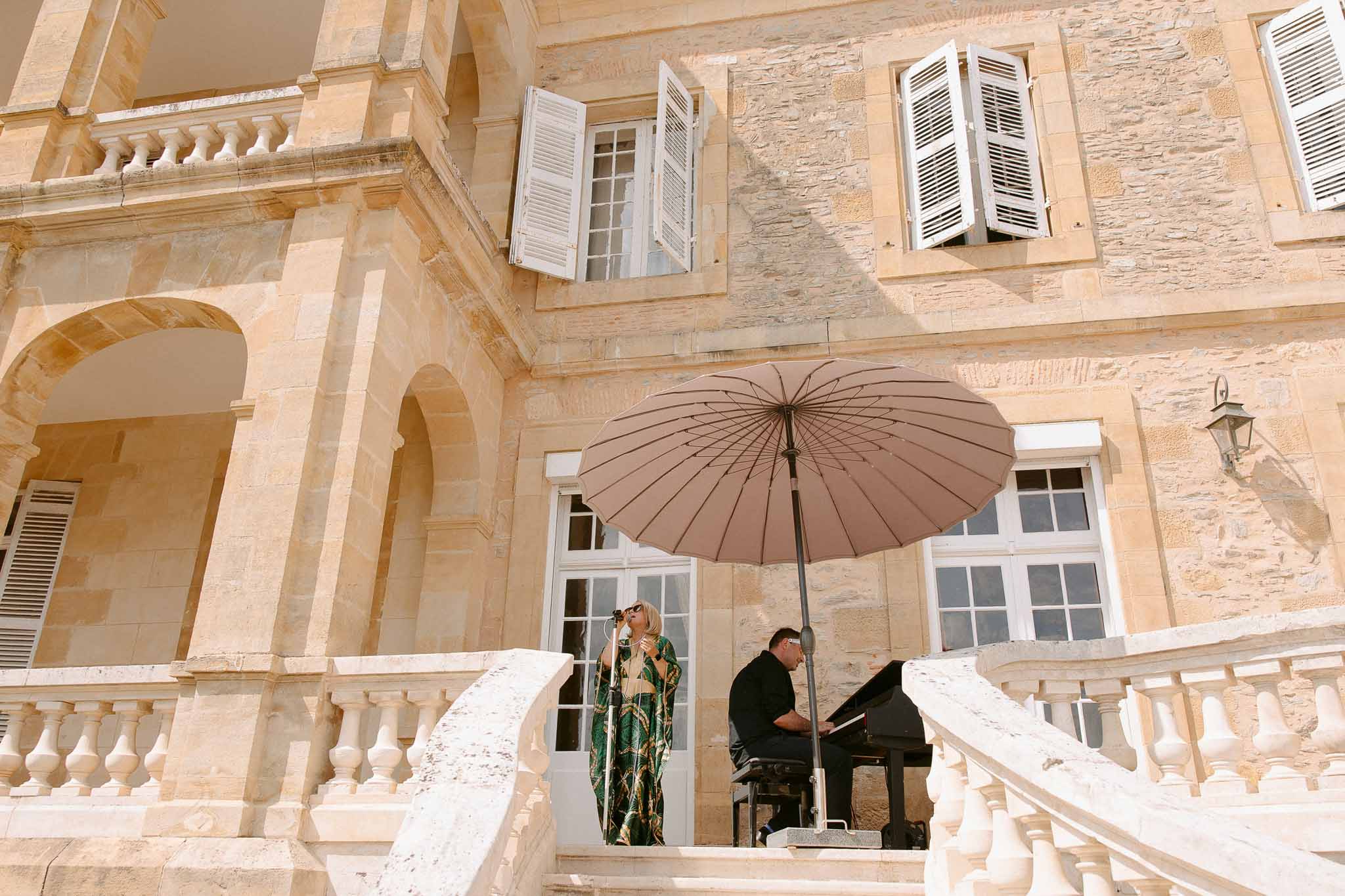 Pianist performing in stone courtyard at European château during wedding reception
