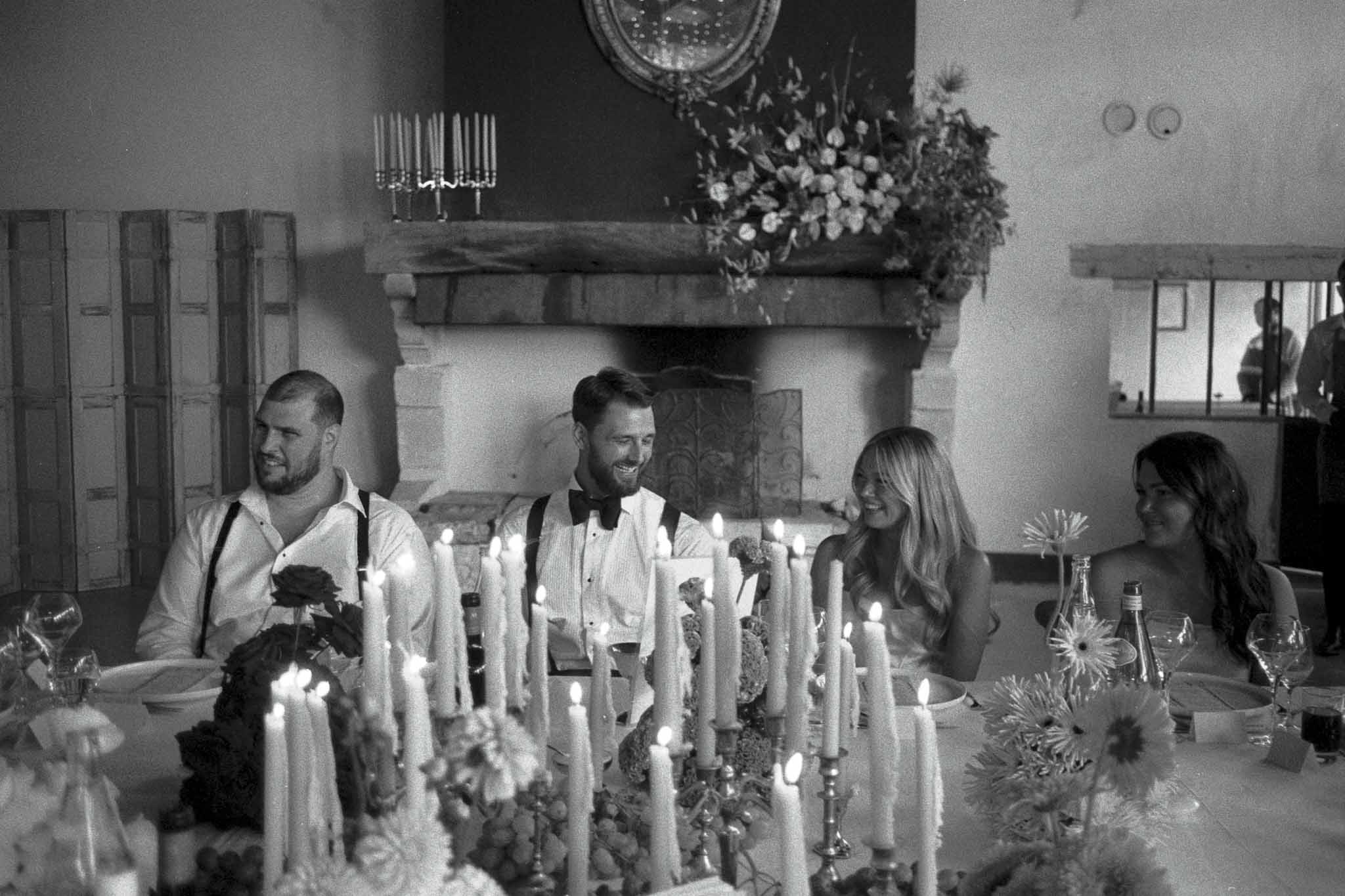 Guests dining at candlelit reception table in historic stone venue with fireplace
