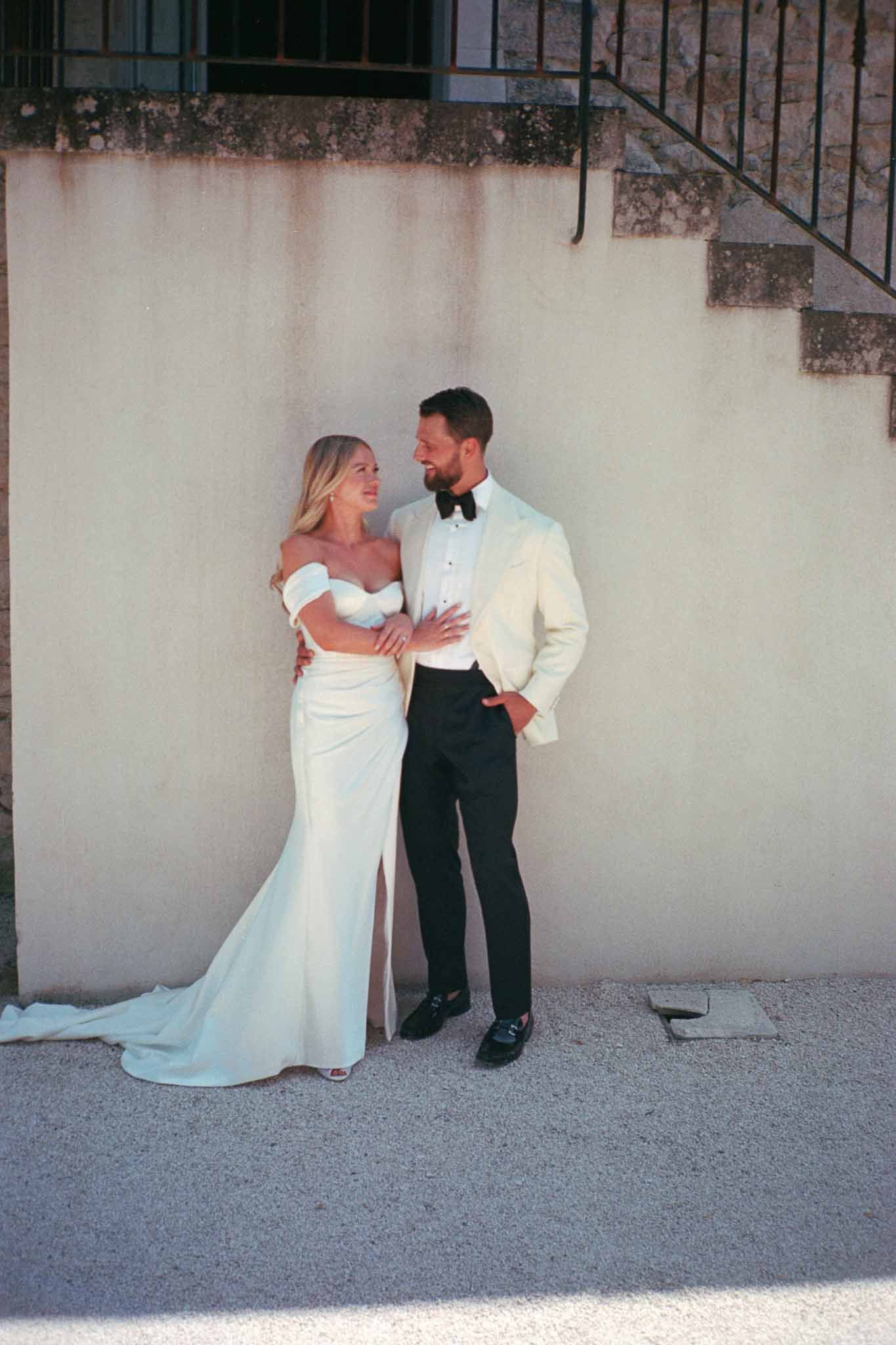 Bride and groom portrait against concrete wall in urban setting