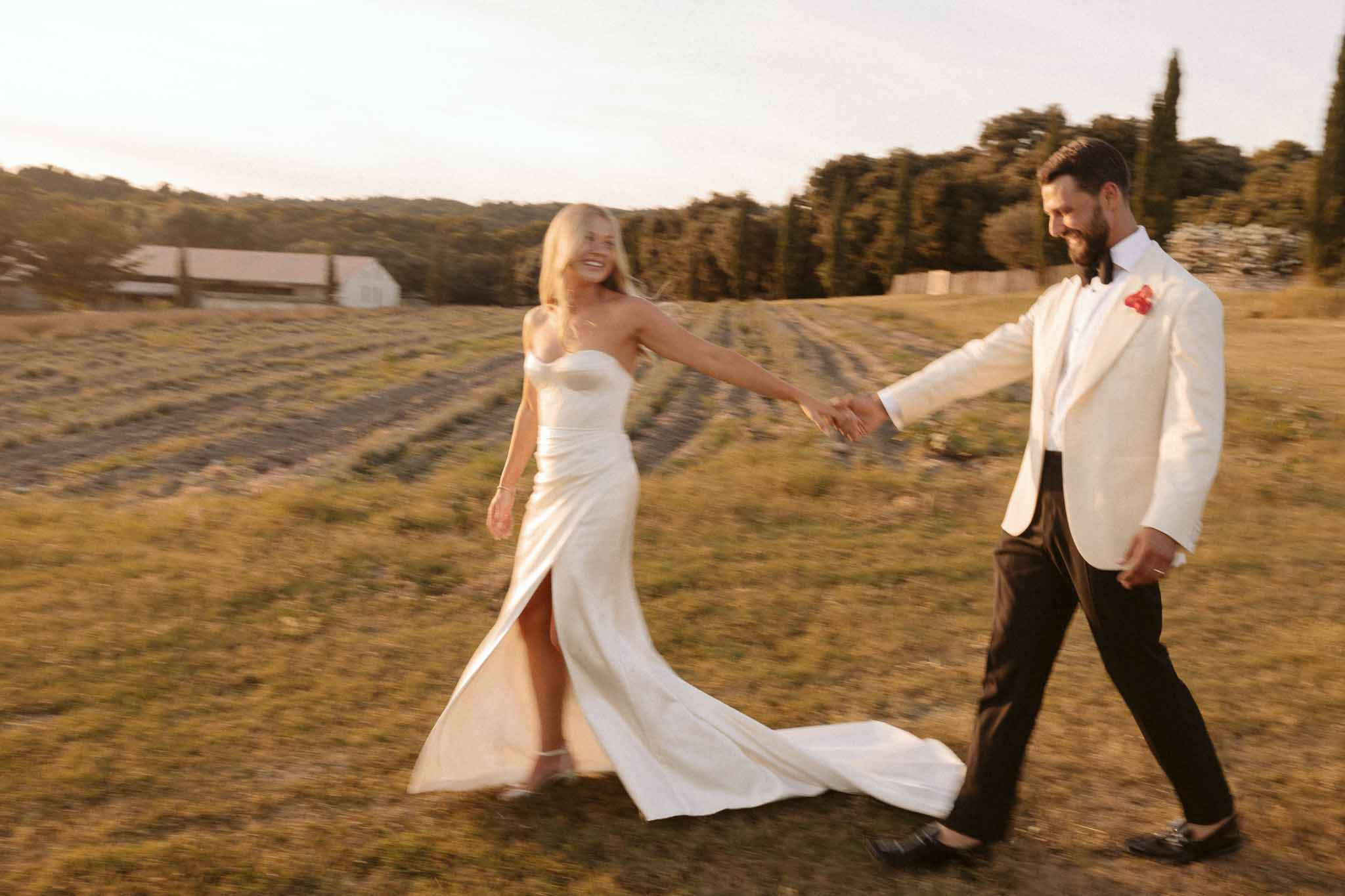 Bride and groom portrait in countryside field during golden hour with flowing dress train