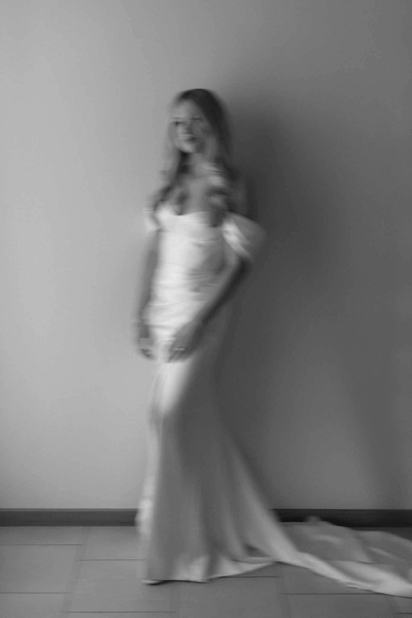 Black and white bridal portrait of bride in fitted gown with train in minimal indoor studio setting