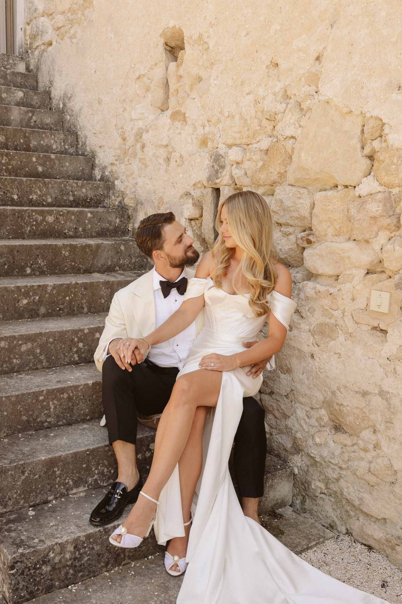Bride and groom sitting on stone steps at historic stone venue