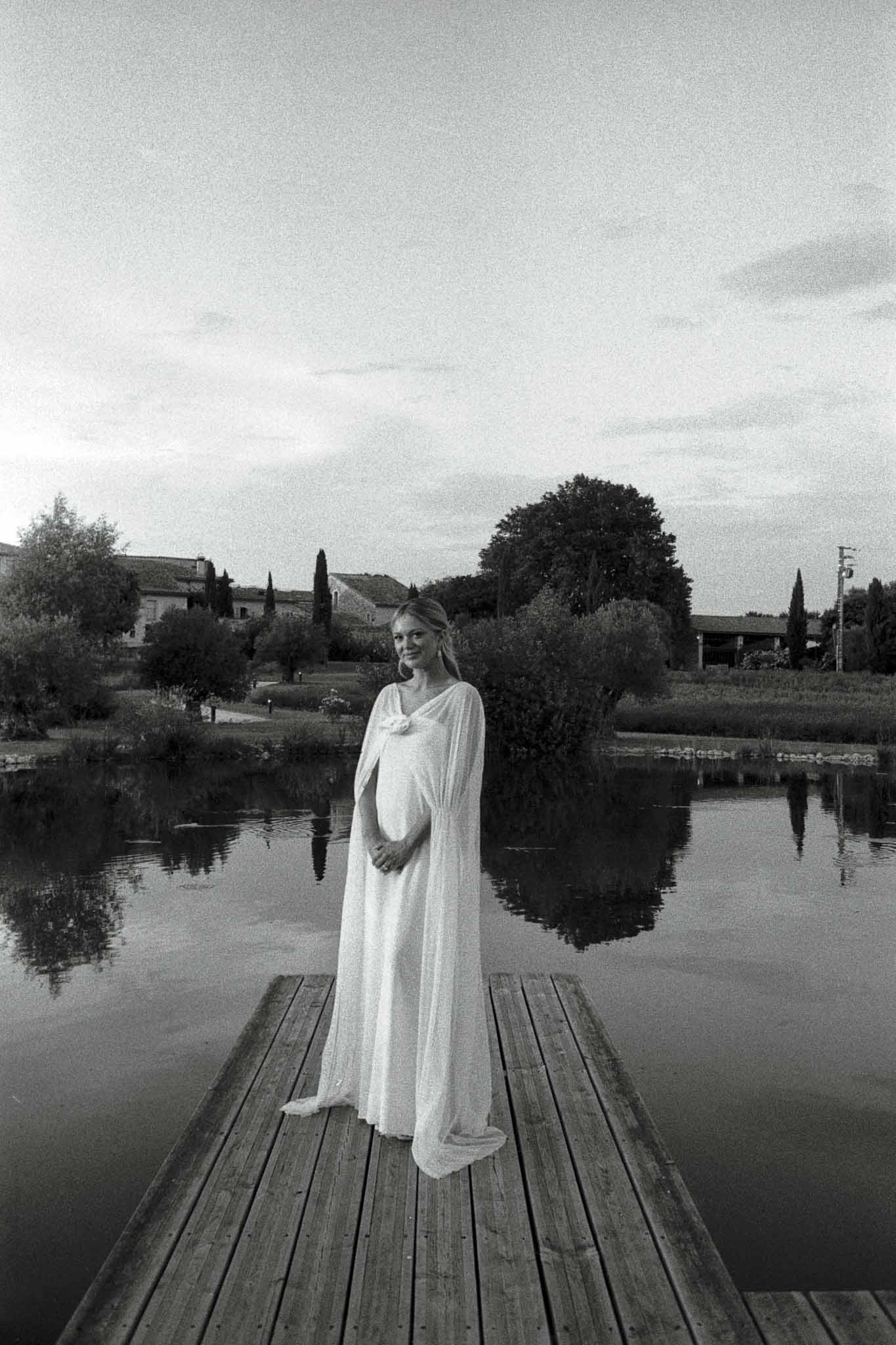 Black and white maternity bridal portrait on wooden dock with Tuscan landscape backdrop