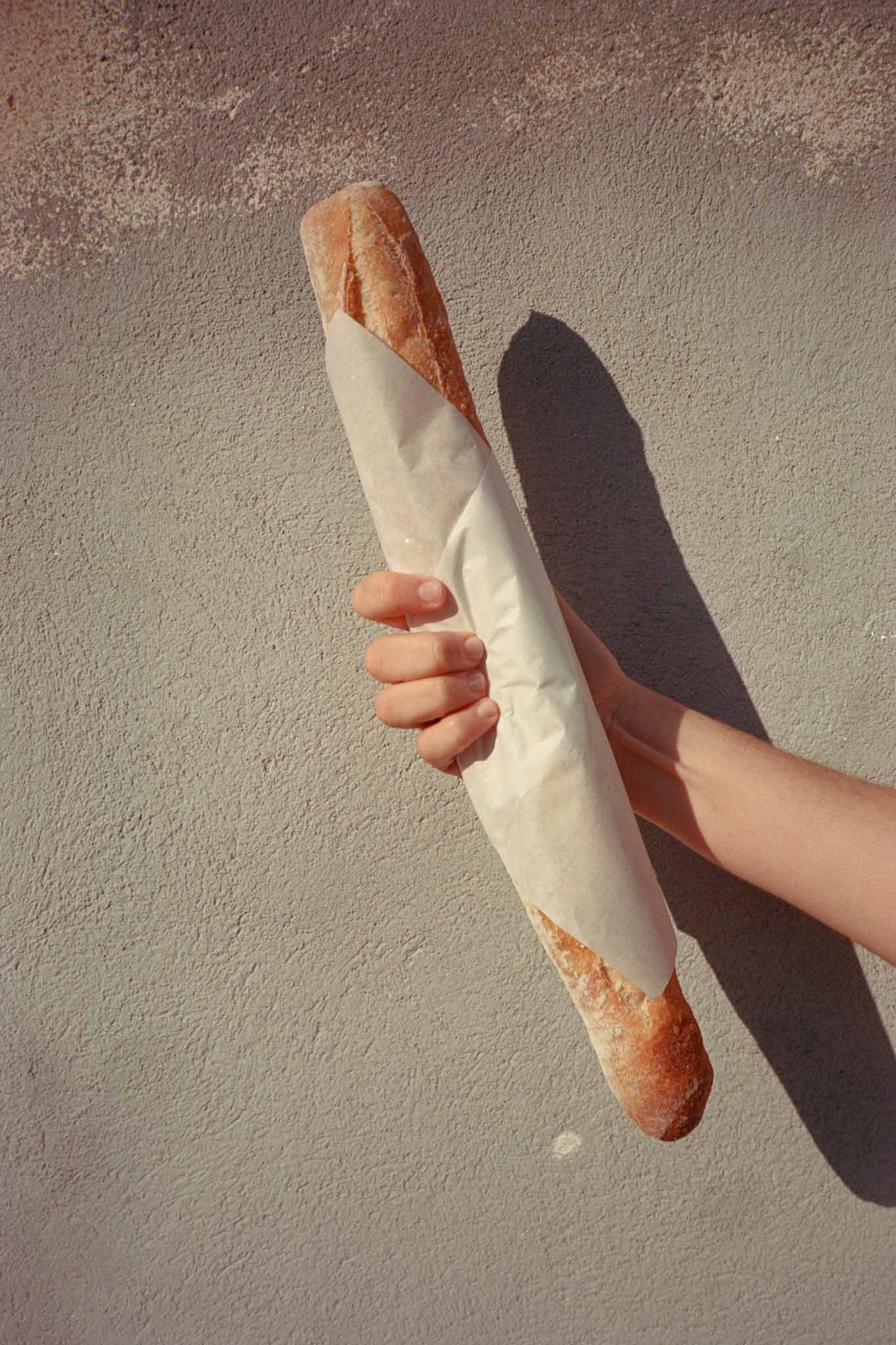 Close-up of crusty French baguette wrapped in paper on concrete surface at wedding reception