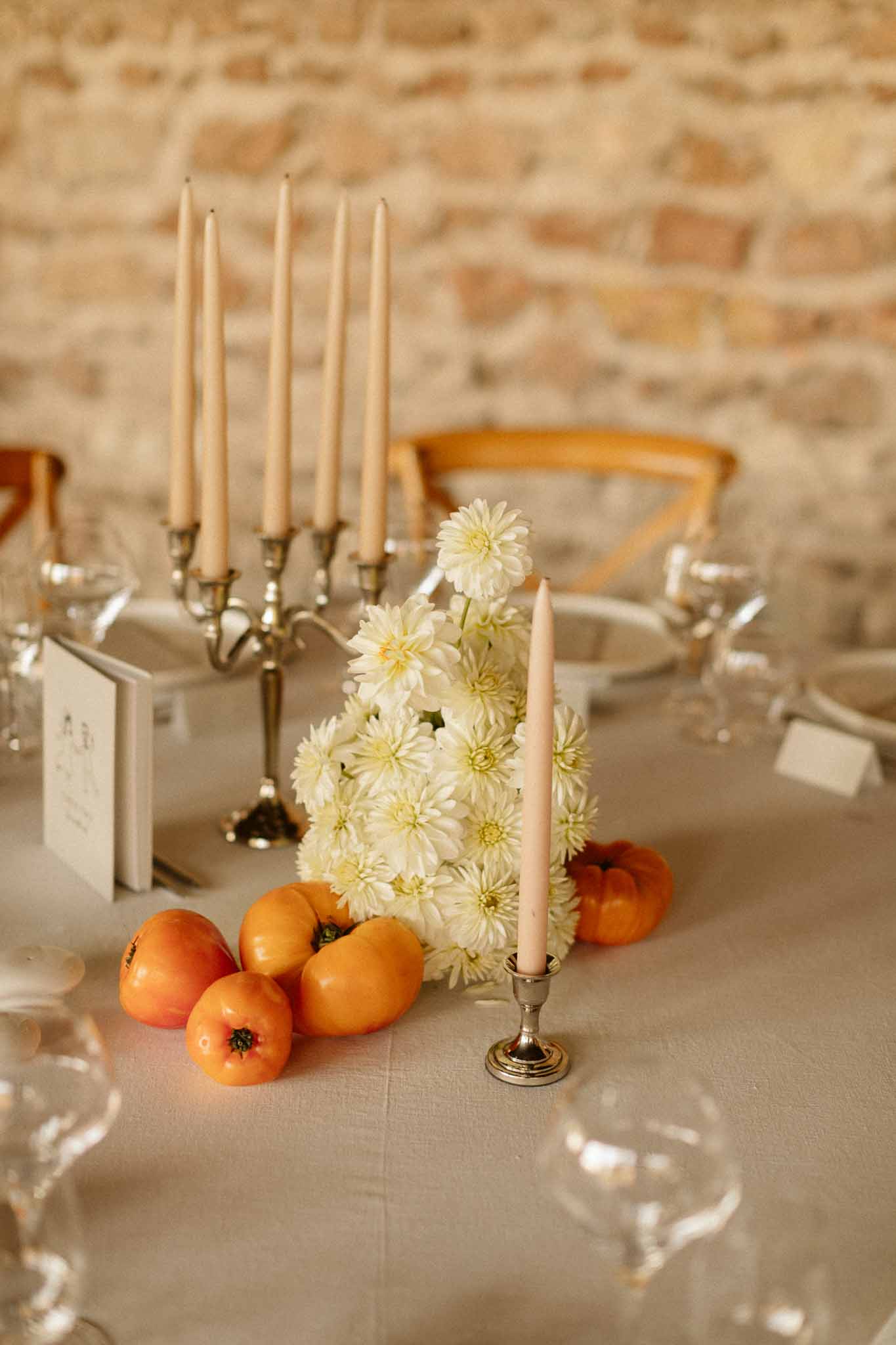 Wedding reception table setting with daisy centerpiece and pomegranate accents at indoor venue