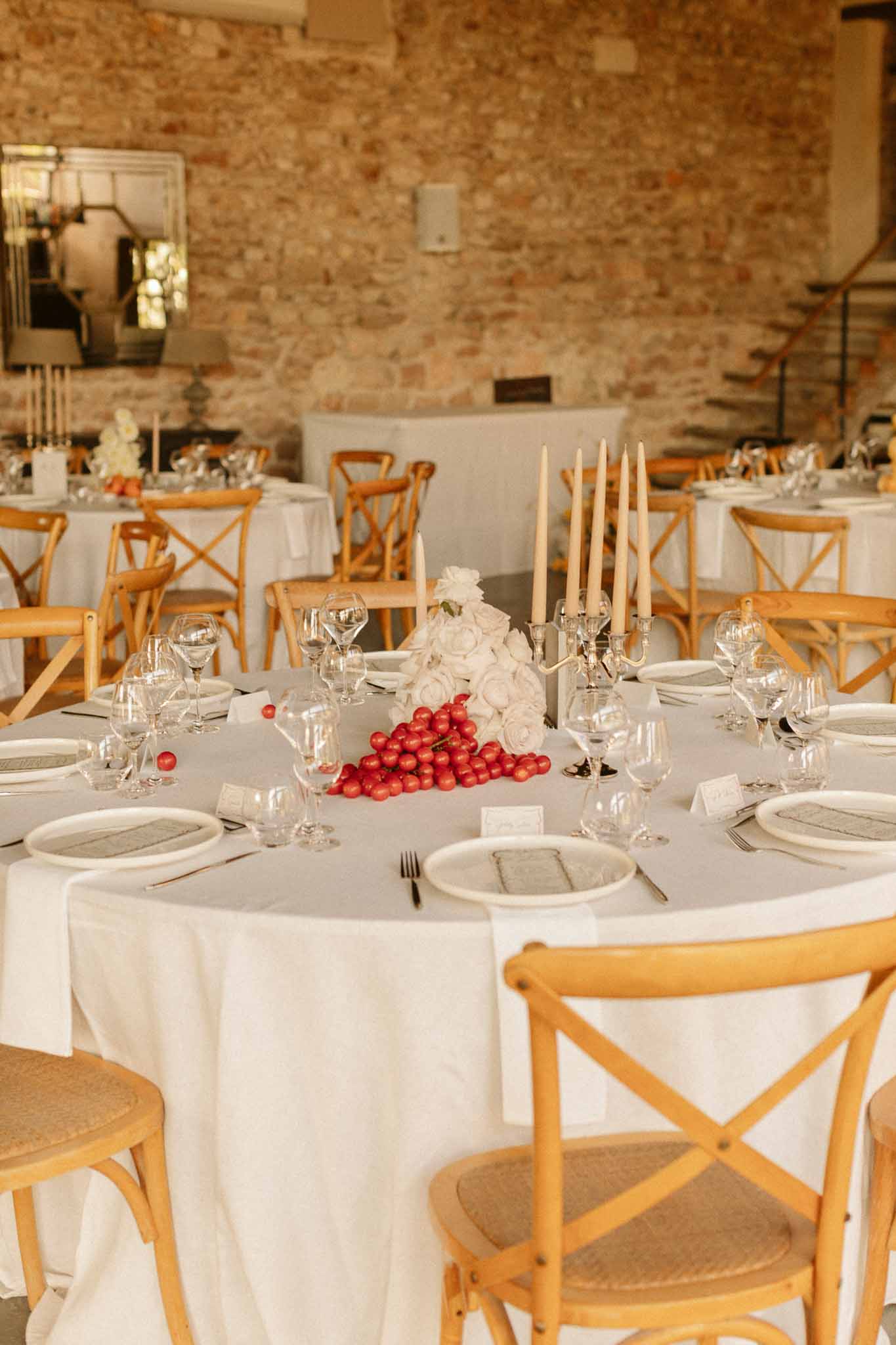 Reception table setup with ivory linens and red accents in exposed brick venue