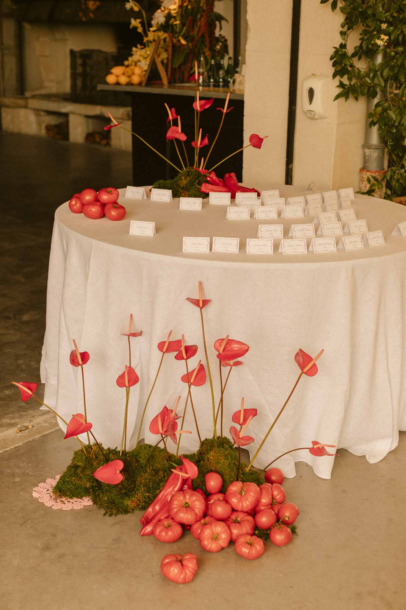 Red anthurium and apple seating chart display at modern industrial wedding venue