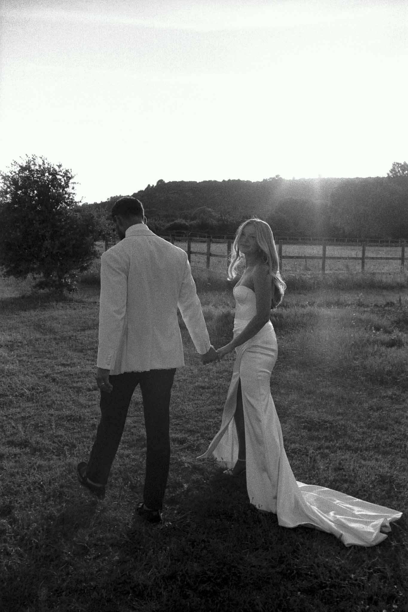 Black and white couple portrait in countryside field with wooden ranch fencing and rolling hills