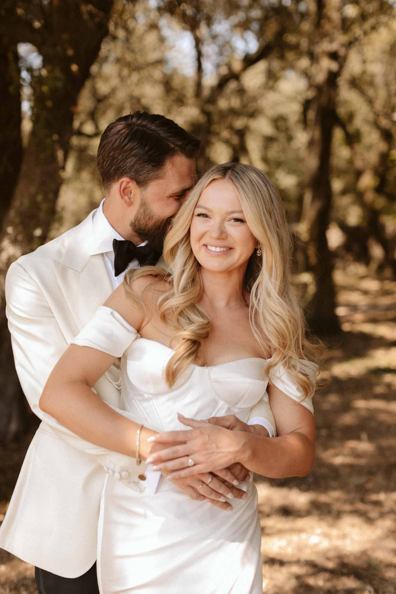 Bride and groom embracing in romantic portrait in tree-lined outdoor setting