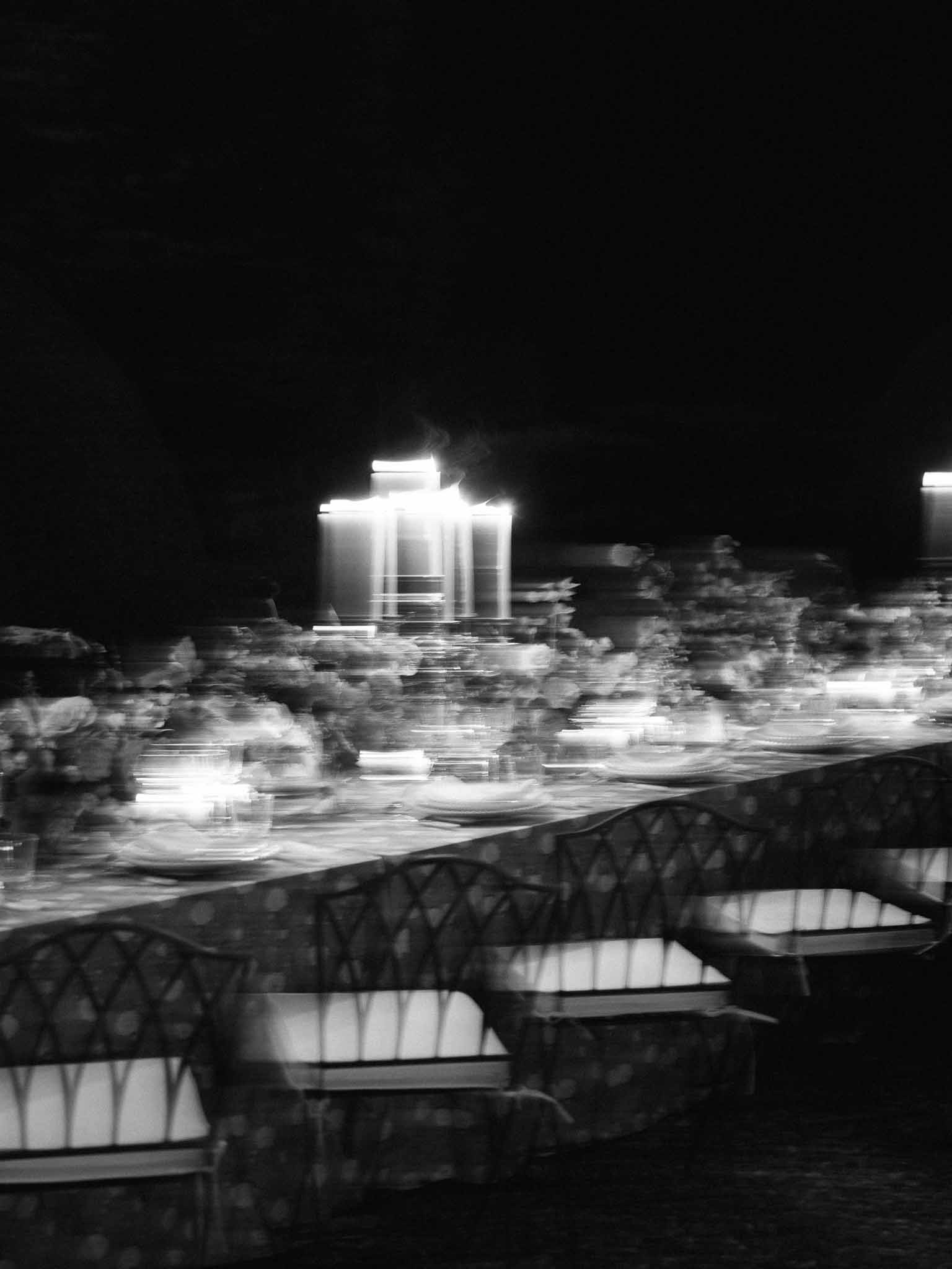 Evening reception table setting with illuminated lanterns at outdoor garden venue