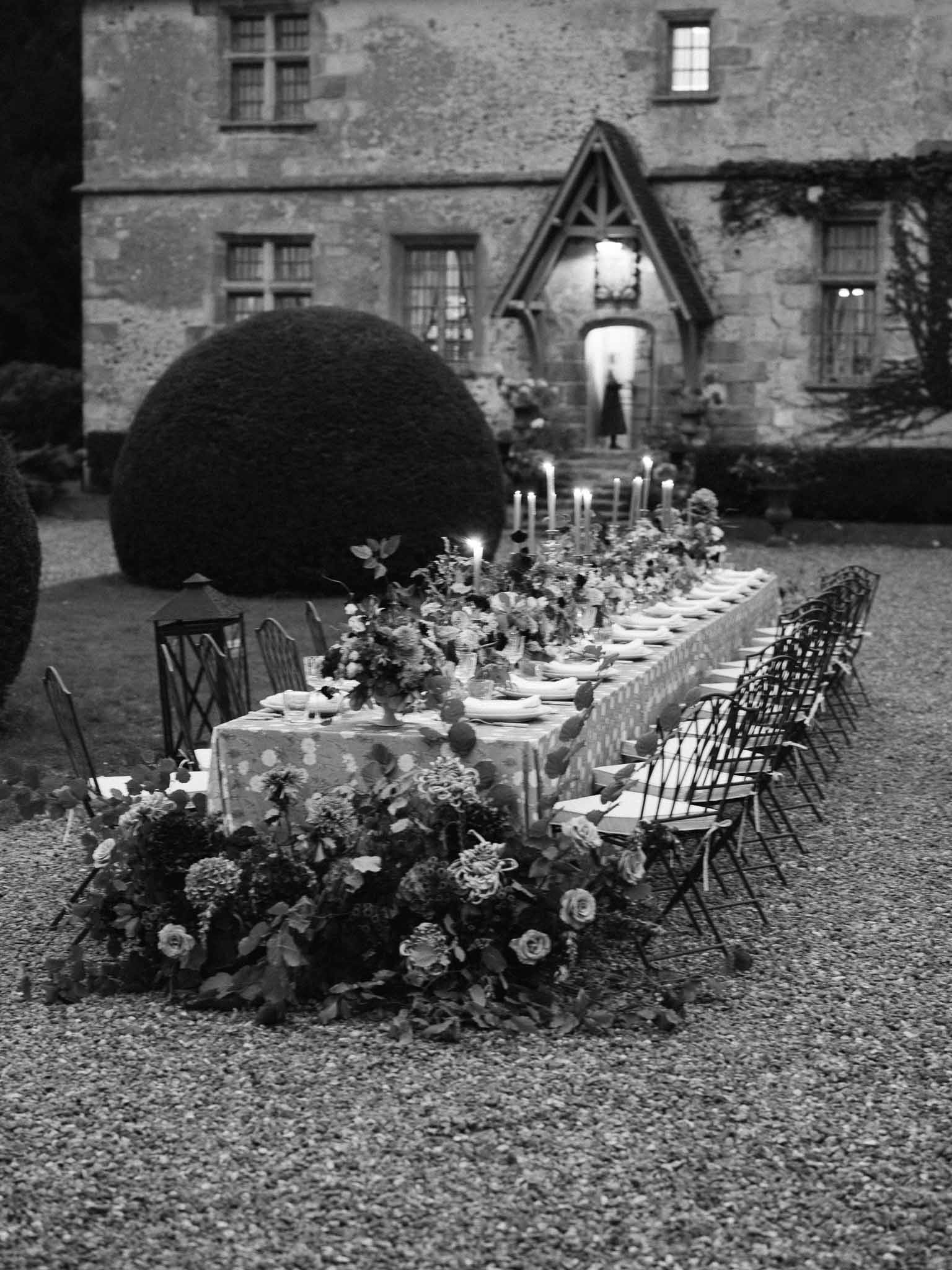 Wedding reception table setup in historic stone courtyard with floral garland runner and candles