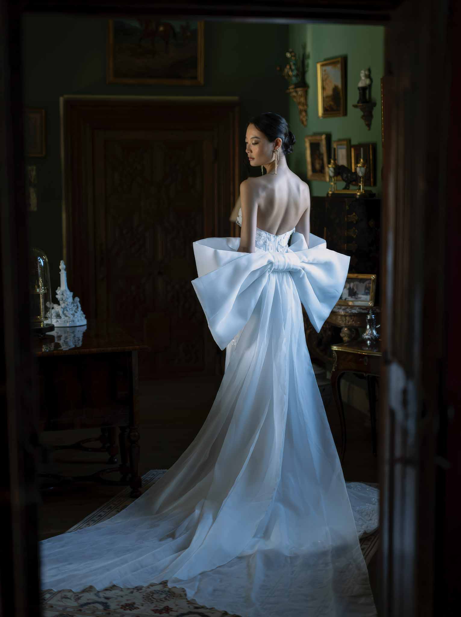 Bride in ivory silk gown with bow detail in traditional sage green interior room