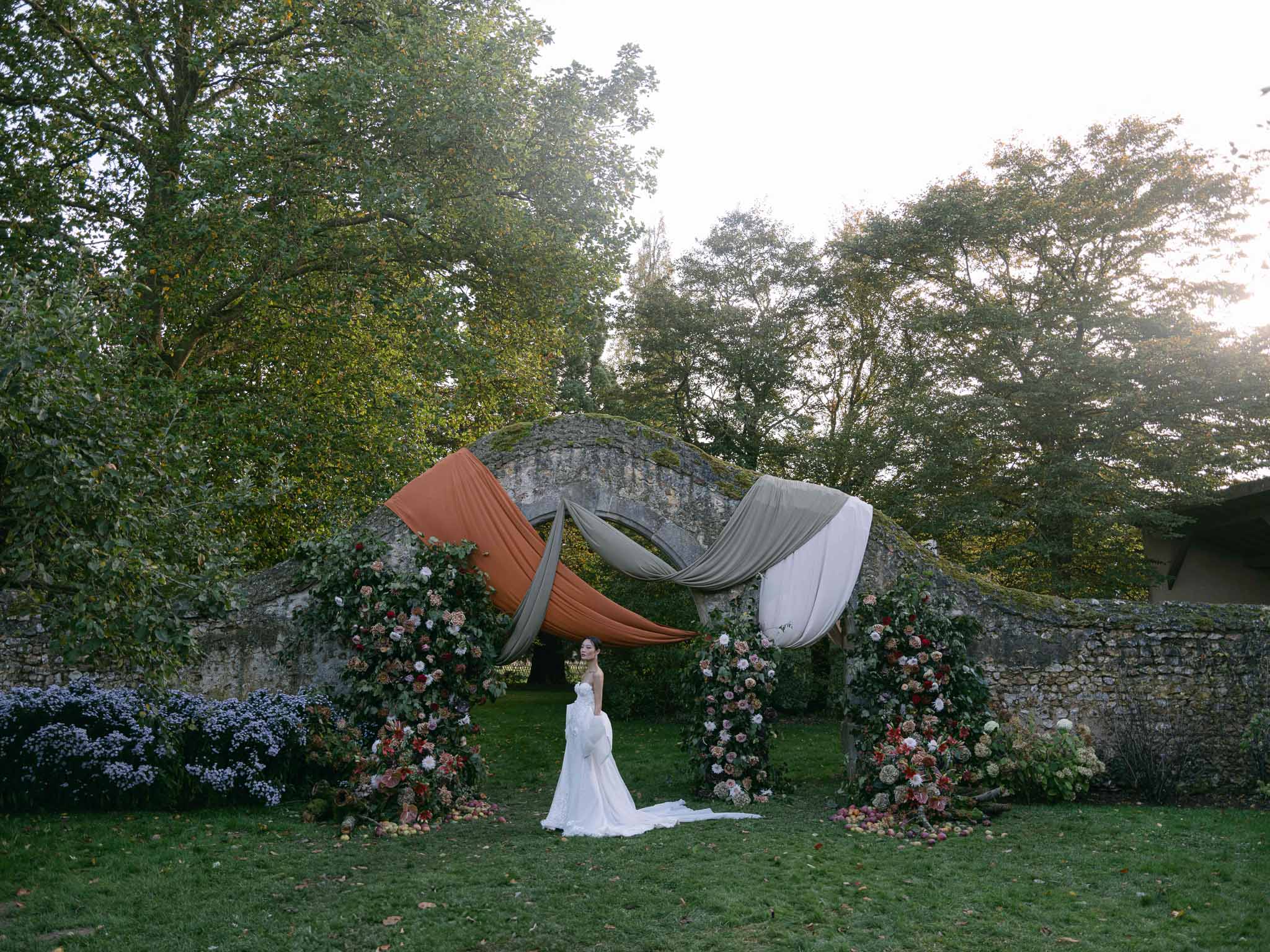 Bride during outdoor ceremony beneath draped archway at historic estate garden
