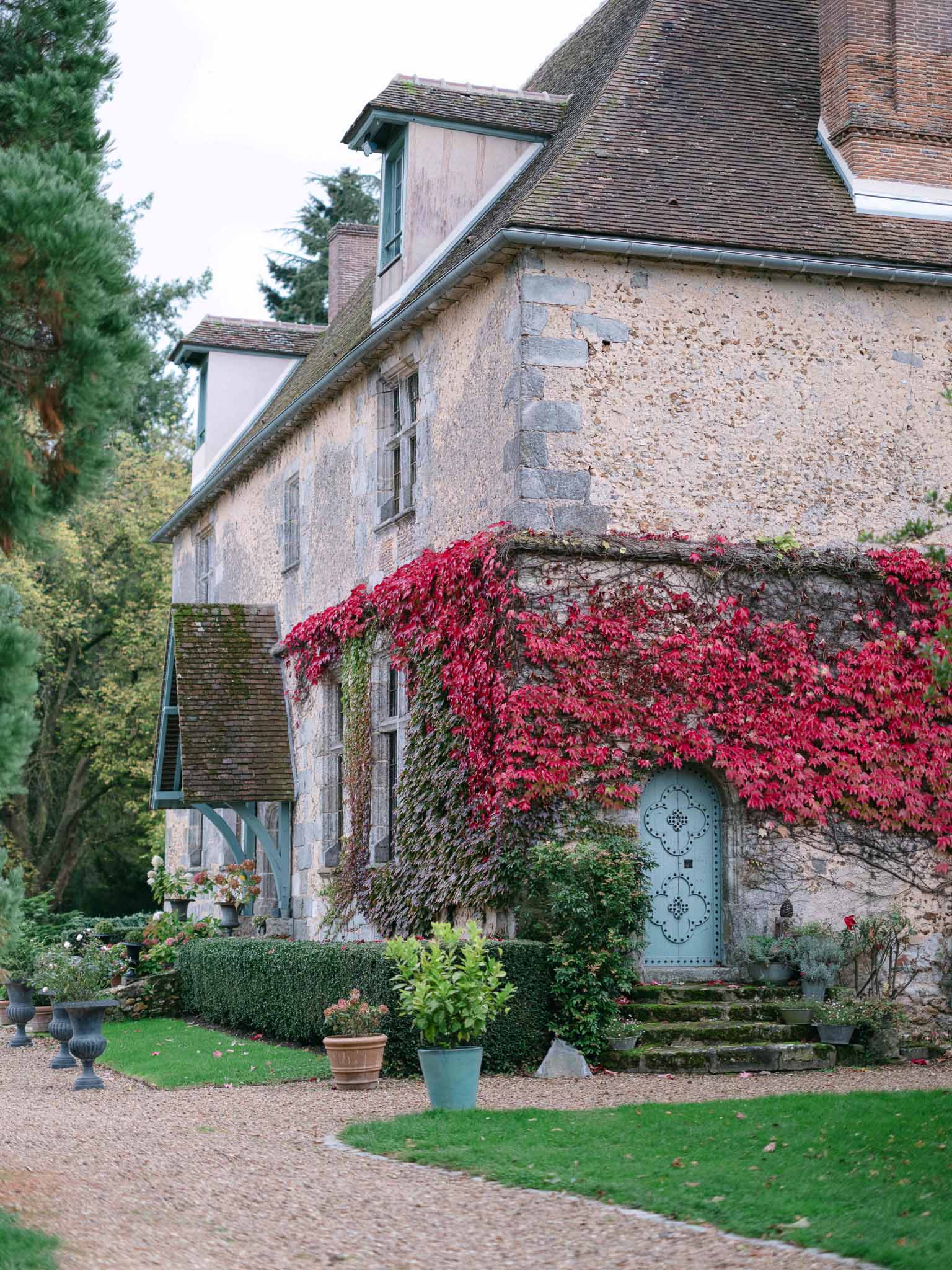 Historic stone manor house with ivy-covered facade and courtyard gardens suitable for wedding venue