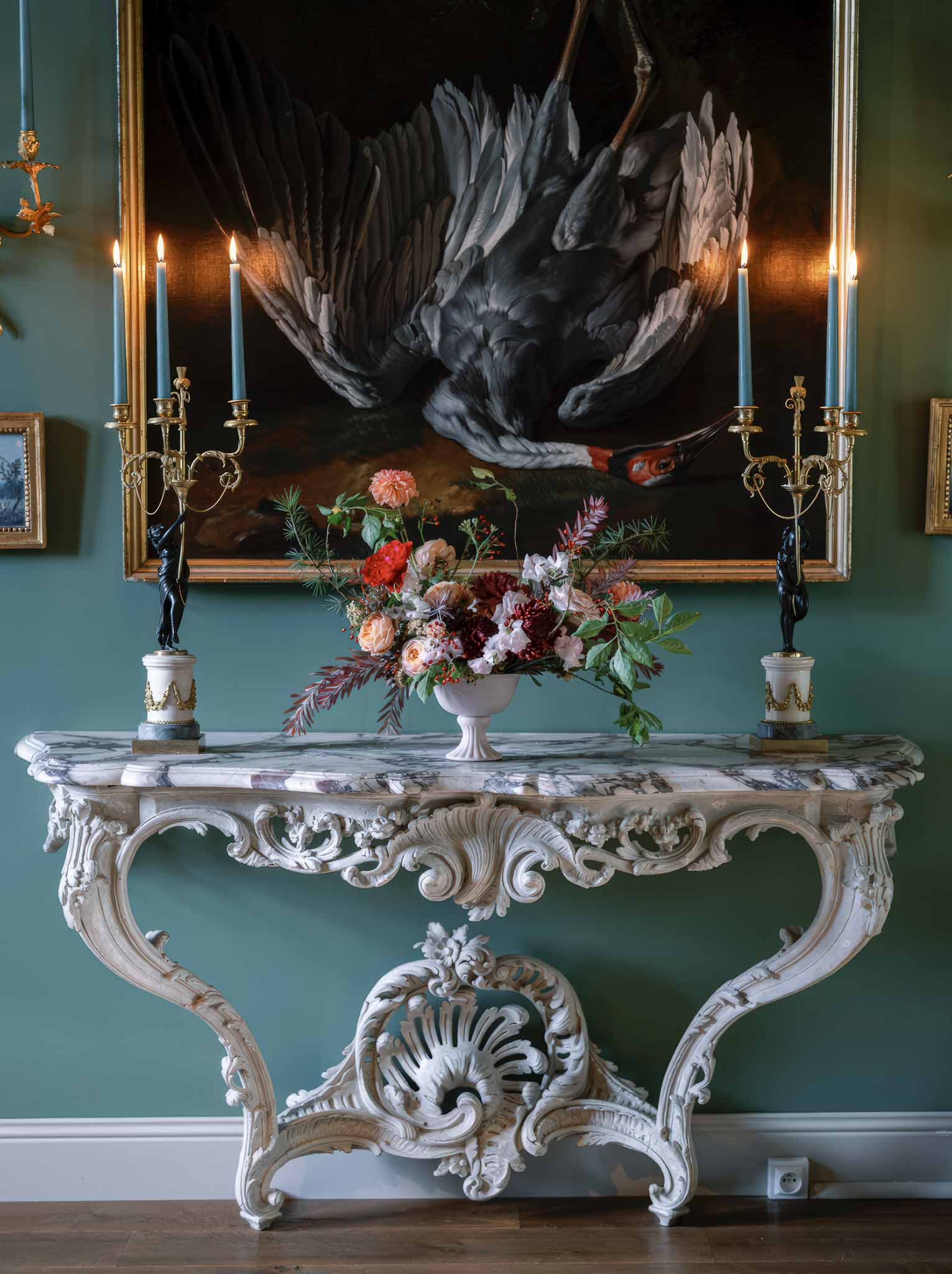 Ornate baroque console table with floral arrangement and candelabras in formal reception venue