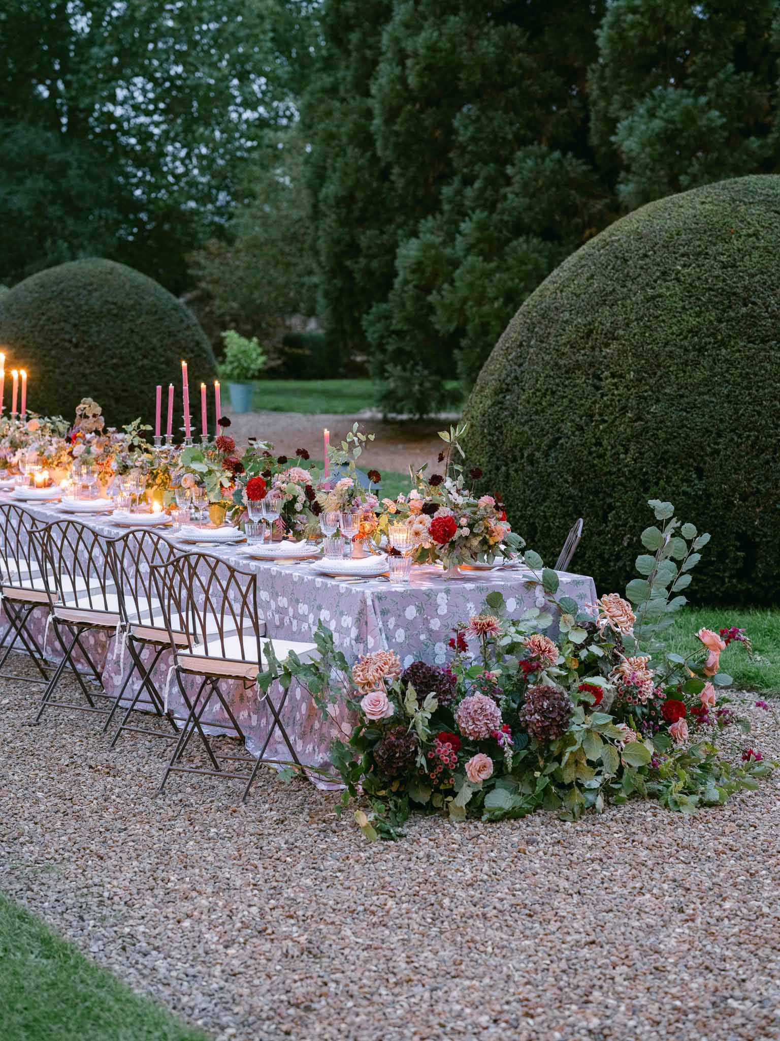 Elegant dinner table setting with floral arrangements in formal French garden courtyard