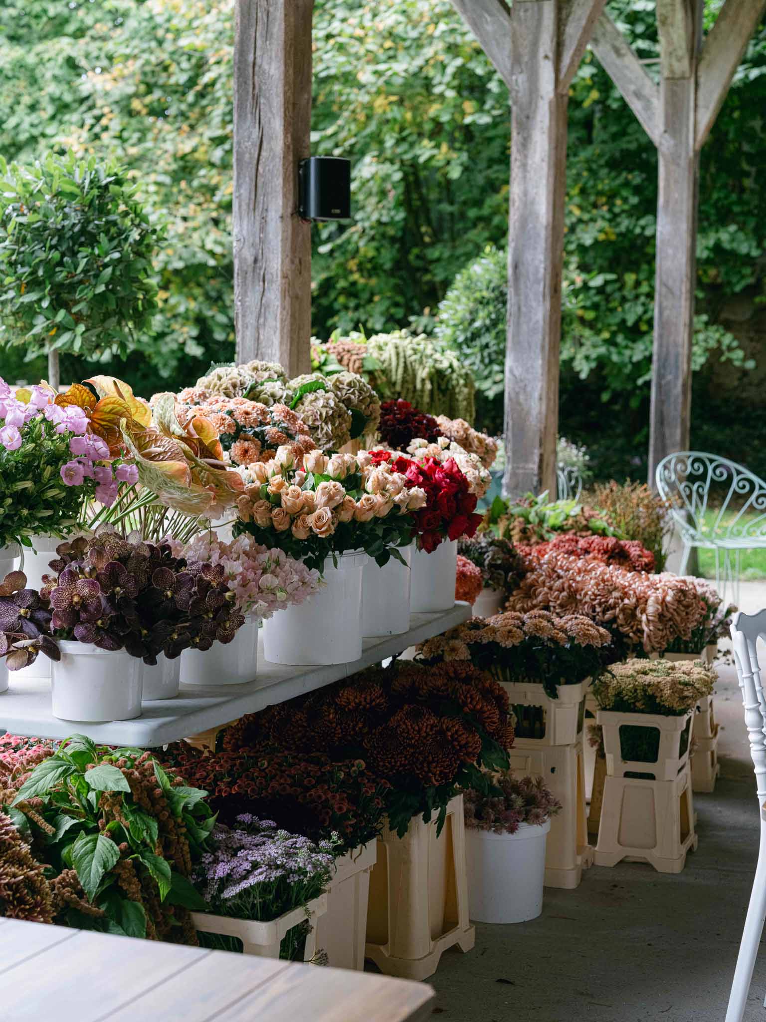 Autumnal floral display arrangement under wooden pergola at outdoor garden wedding reception