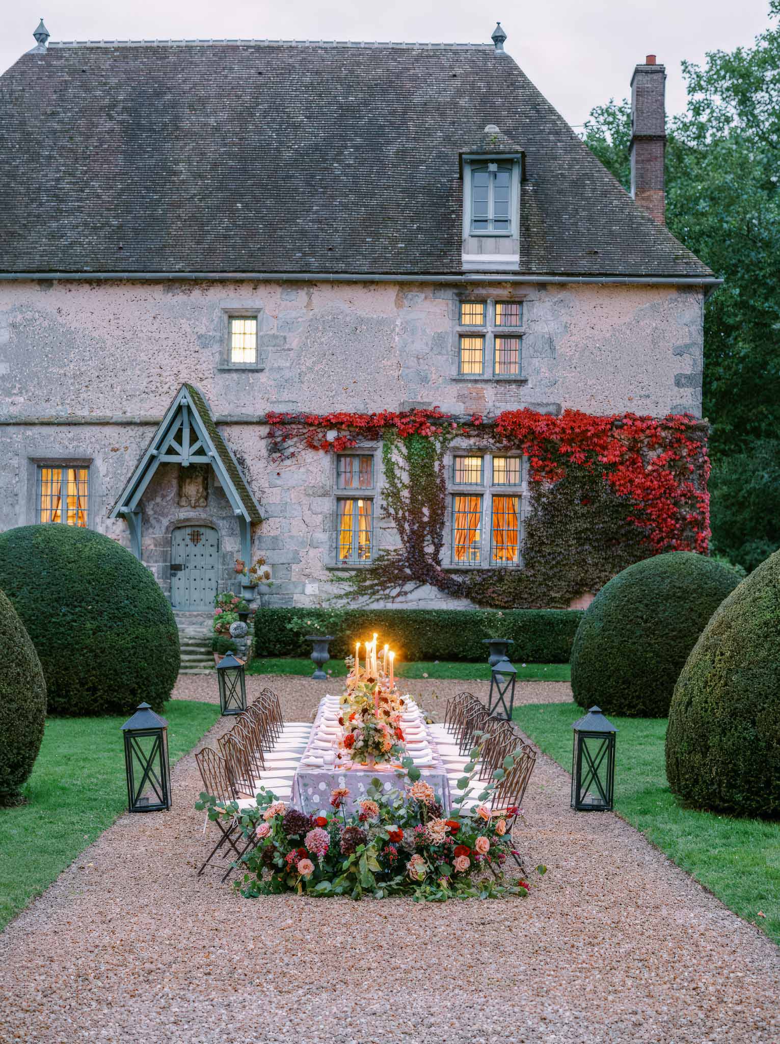 Outdoor reception table setting with floral centerpiece at historic stone manor house gardens