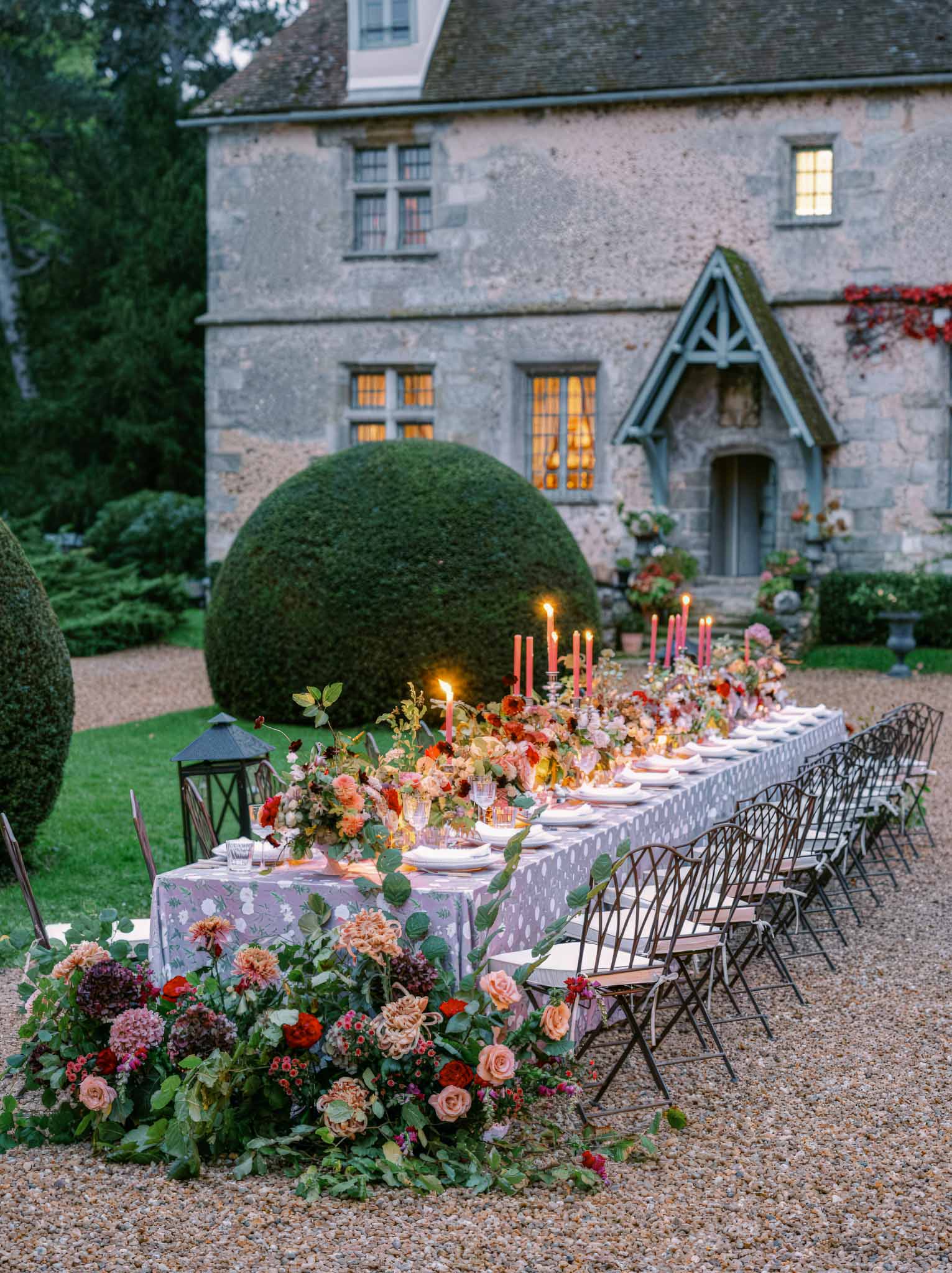 Reception table setting with floral centerpieces in historic stone manor courtyard at twilight