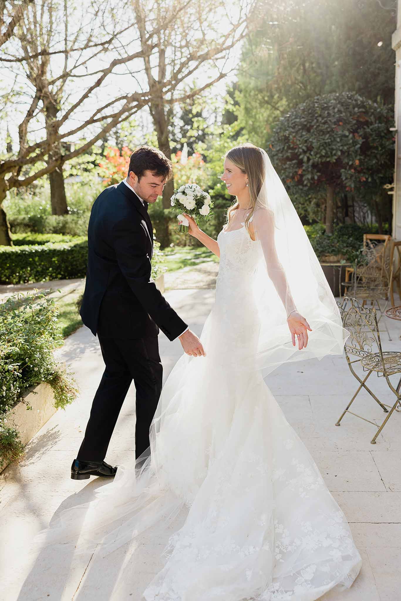 Bride and groom walking together through formal garden courtyard at European-style wedding venue