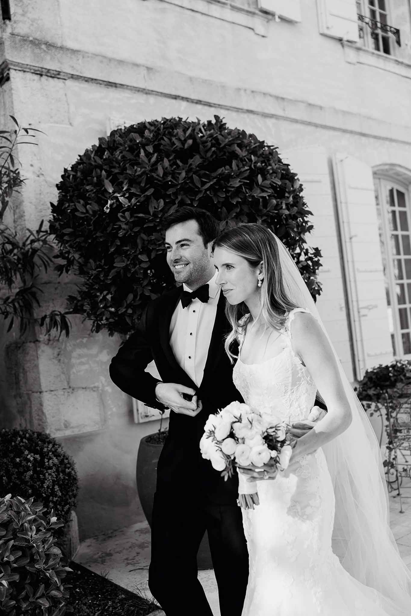 Bride and groom portrait against classical stone building with formal gardens