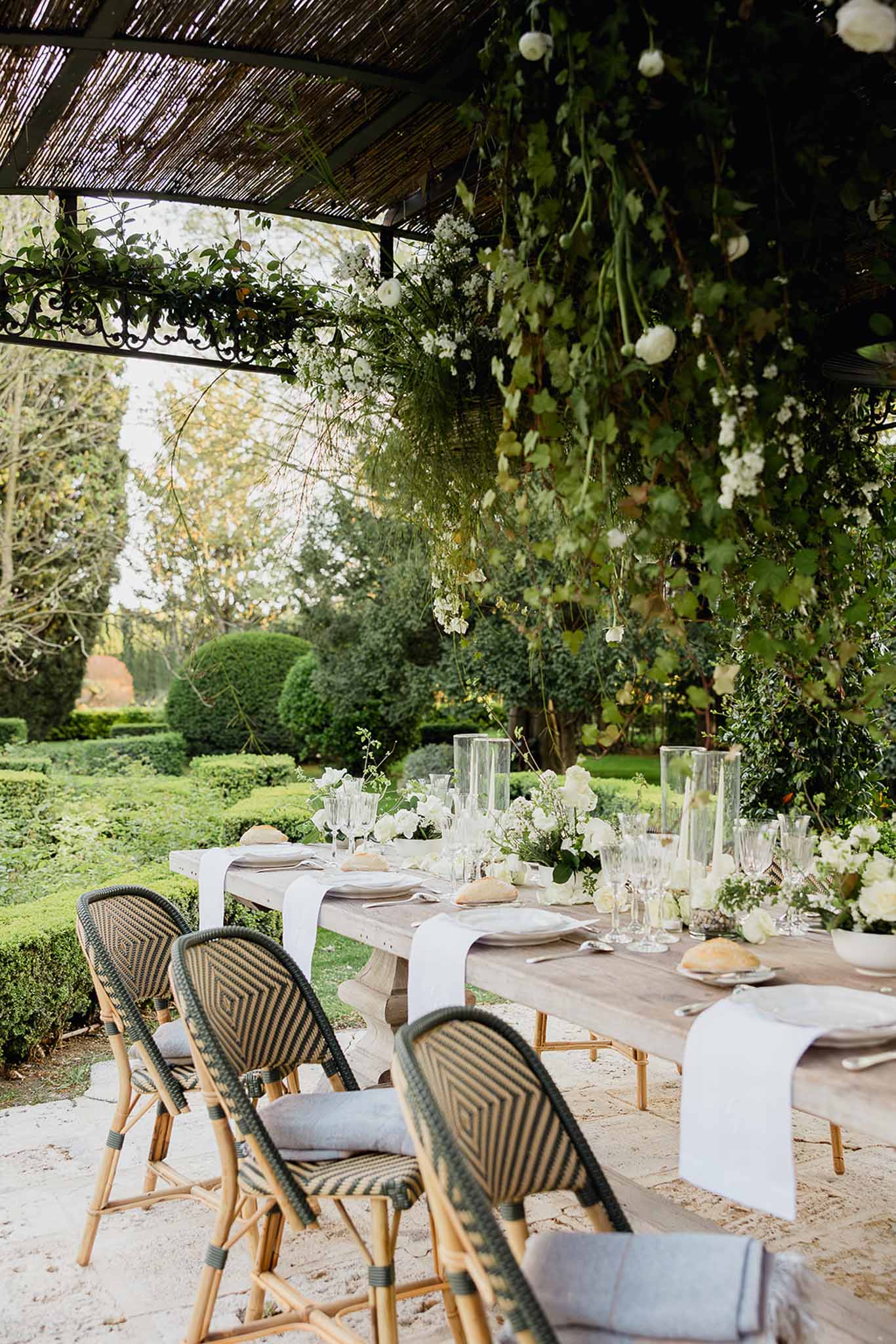 Elegant reception tablescape with white florals under garden pergola