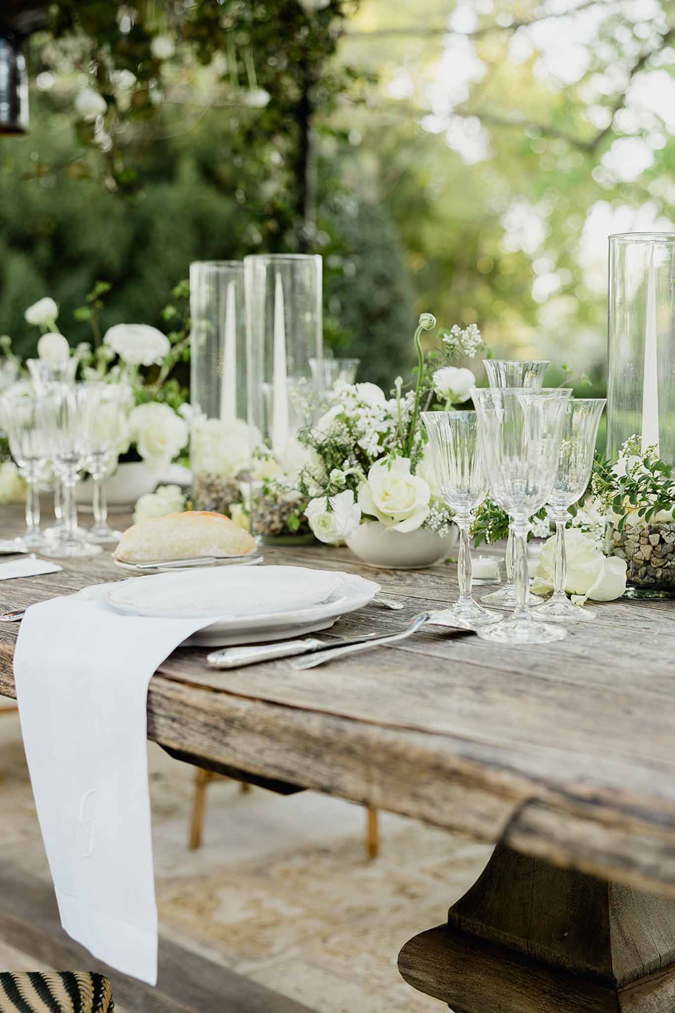 White and green reception table setting with roses and baby's breath at garden wedding venue