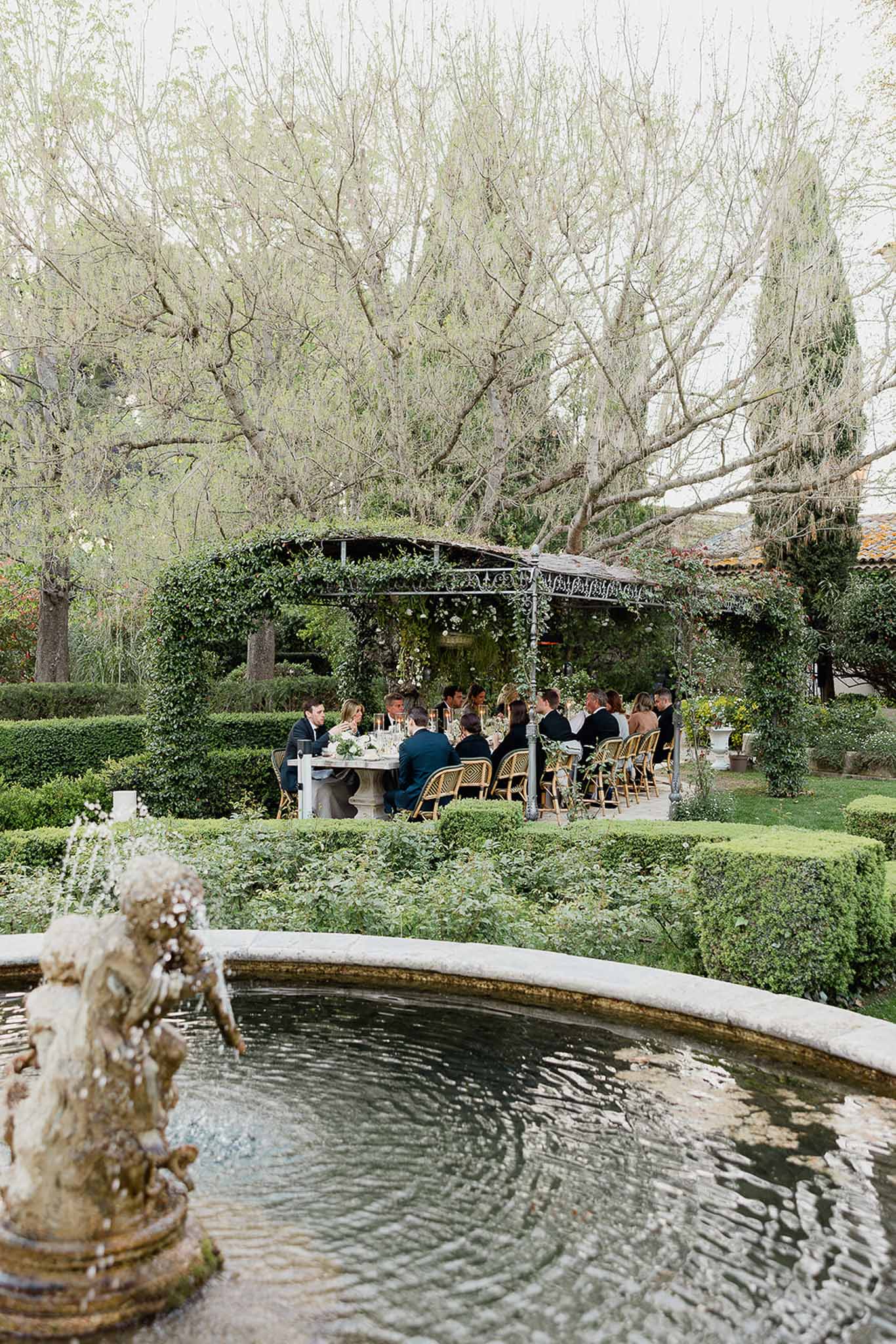 Wedding reception dinner at formal garden venue with pergola and fountain