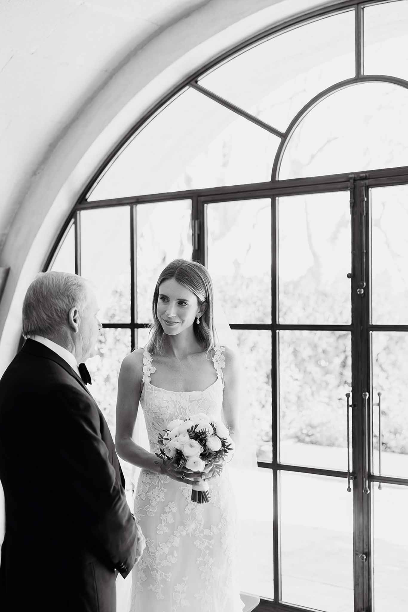 Bride with father in intimate moment inside modern glass venue with curved architecture