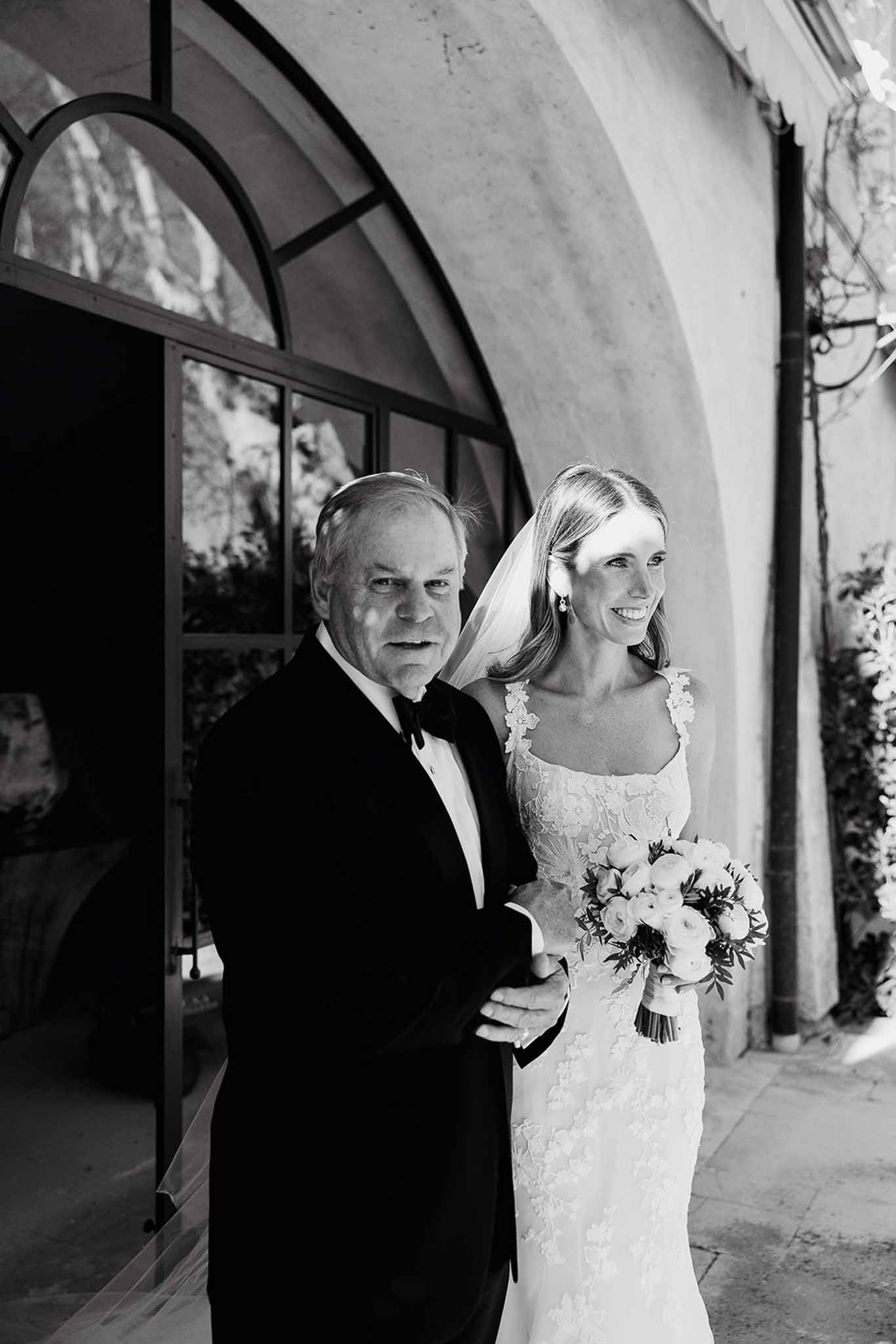 Bride and groom posing together outside modern venue with curved architecture