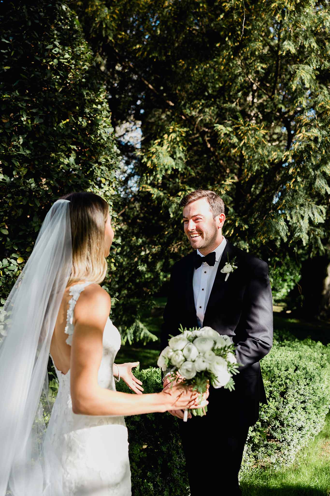 Bride and groom sharing intimate moment during outdoor garden ceremony under natural ivy archway