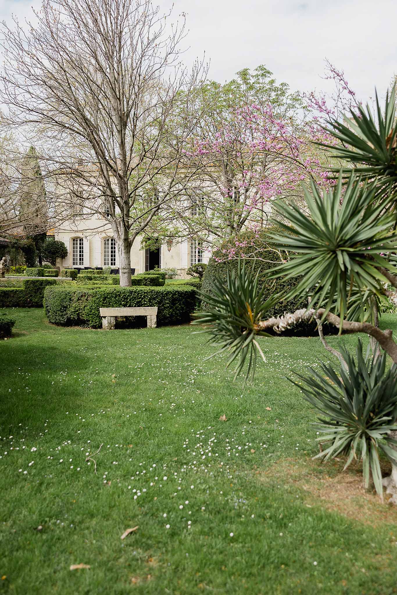 Formal garden venue with cream building and manicured grounds featuring flowering trees and stone pathways