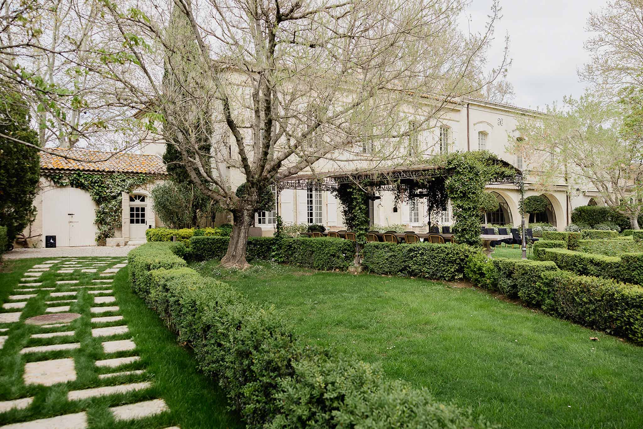 French provincial estate courtyard with stone buildings, arched loggias, and manicured lawn