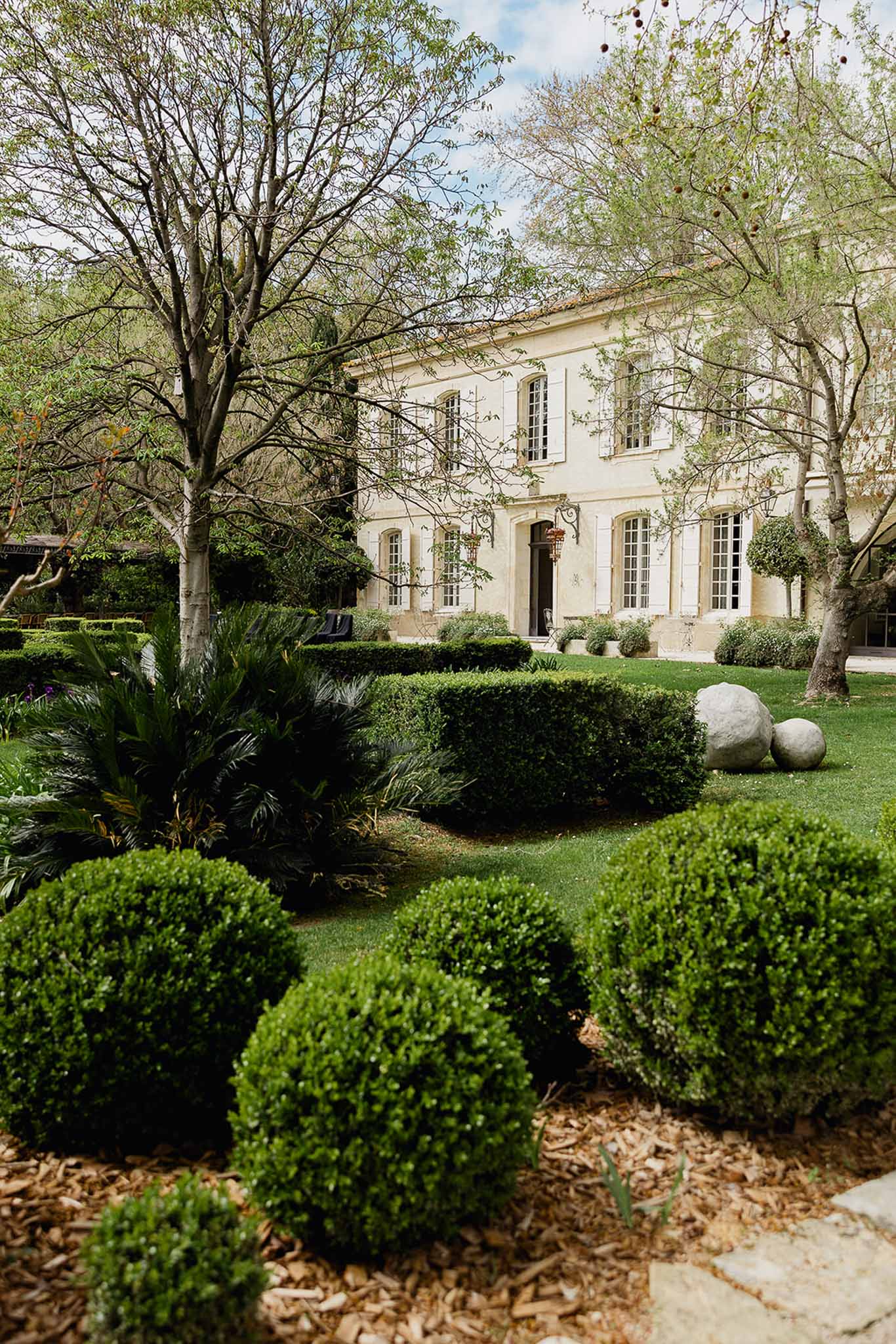 Classical cream stone château exterior with formal gardens and mature trees at French country estate
