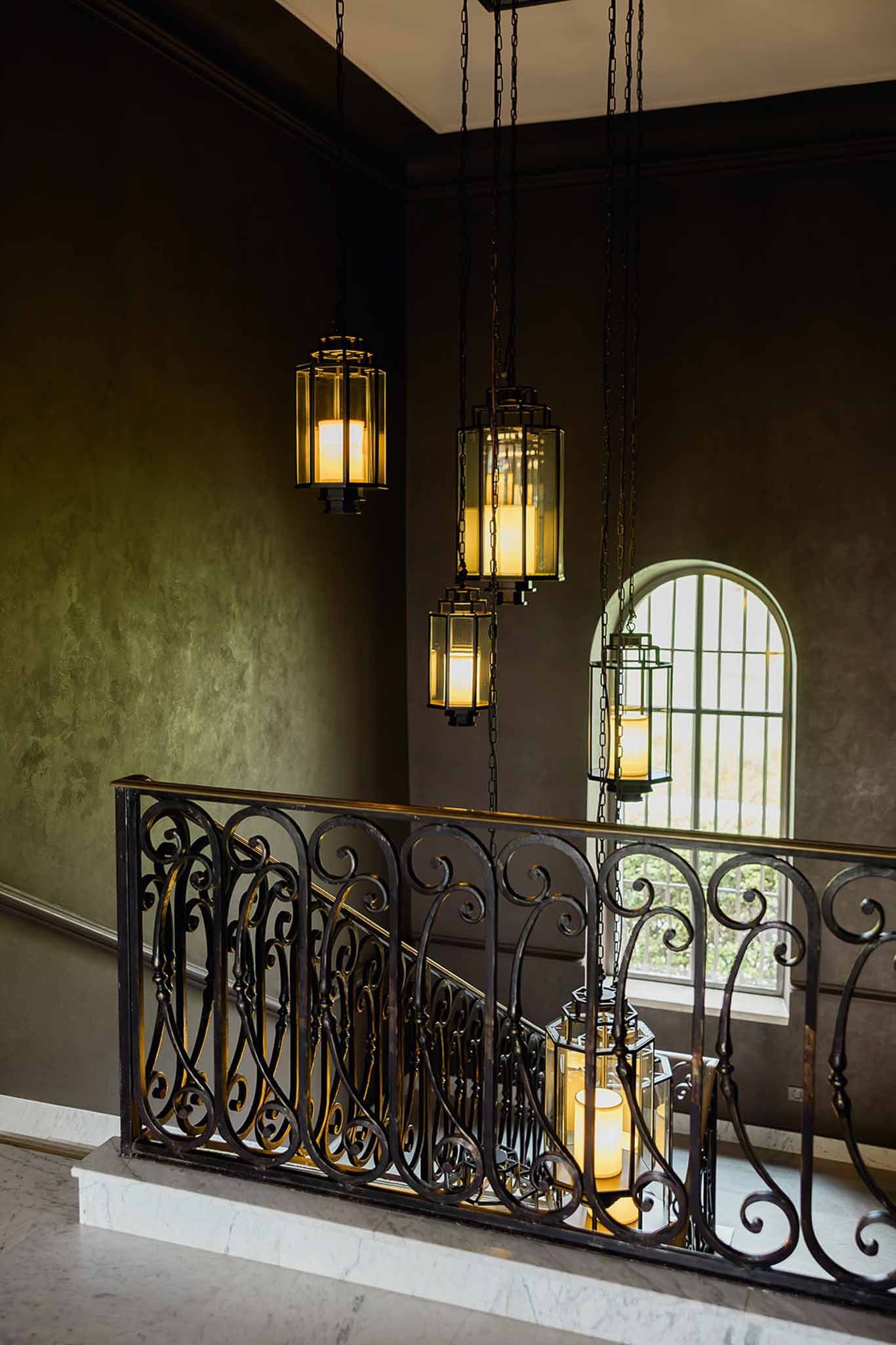 Interior architectural details with brass pendant lighting and wrought iron railings at wedding venue