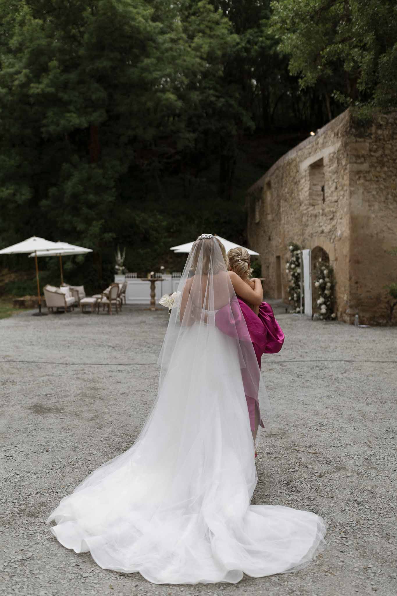 Bride with bridesmaid in historic stone courtyard with arched windows and ivy