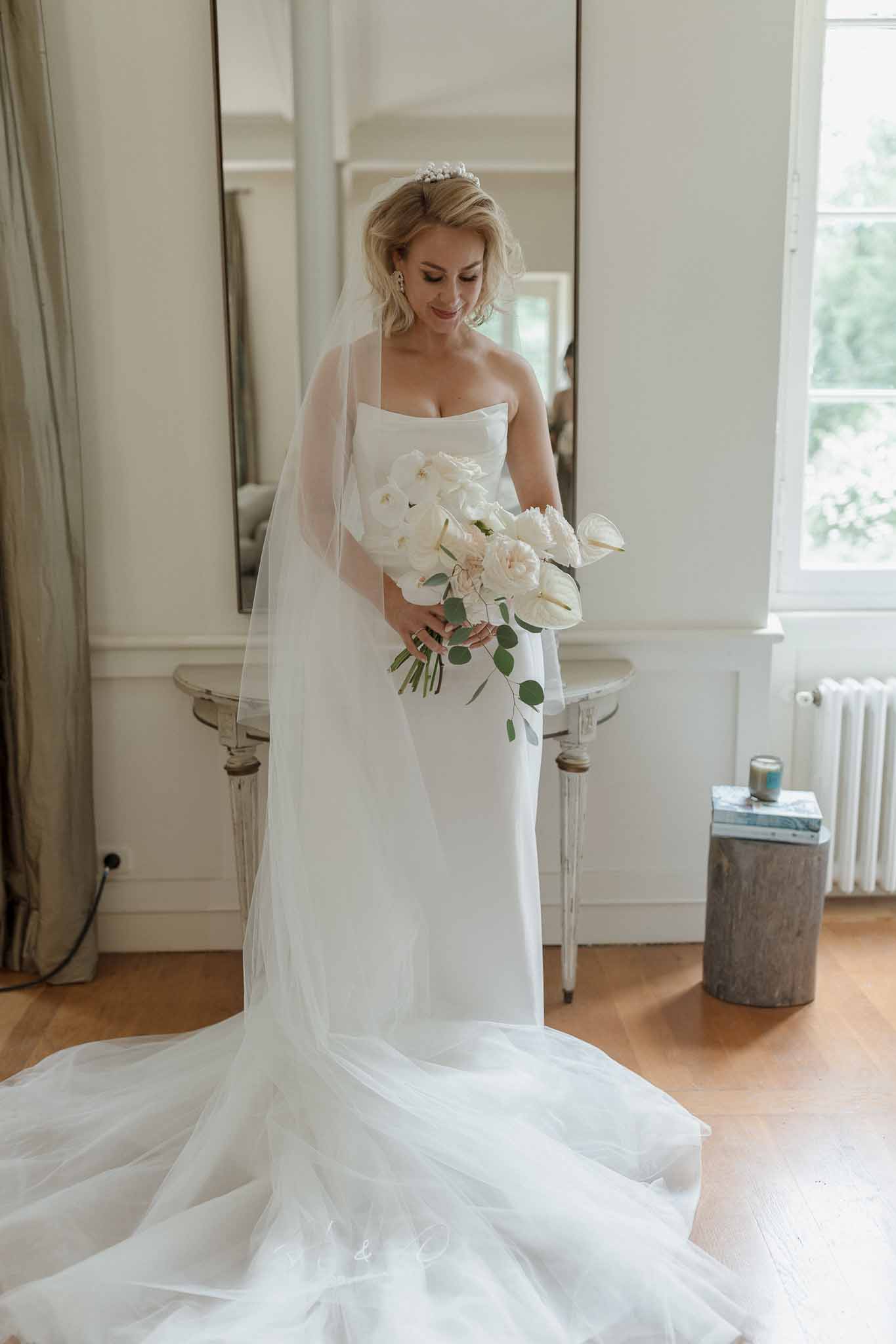 Bride in ivory gown with bouquet during getting ready moment in classical dressing room