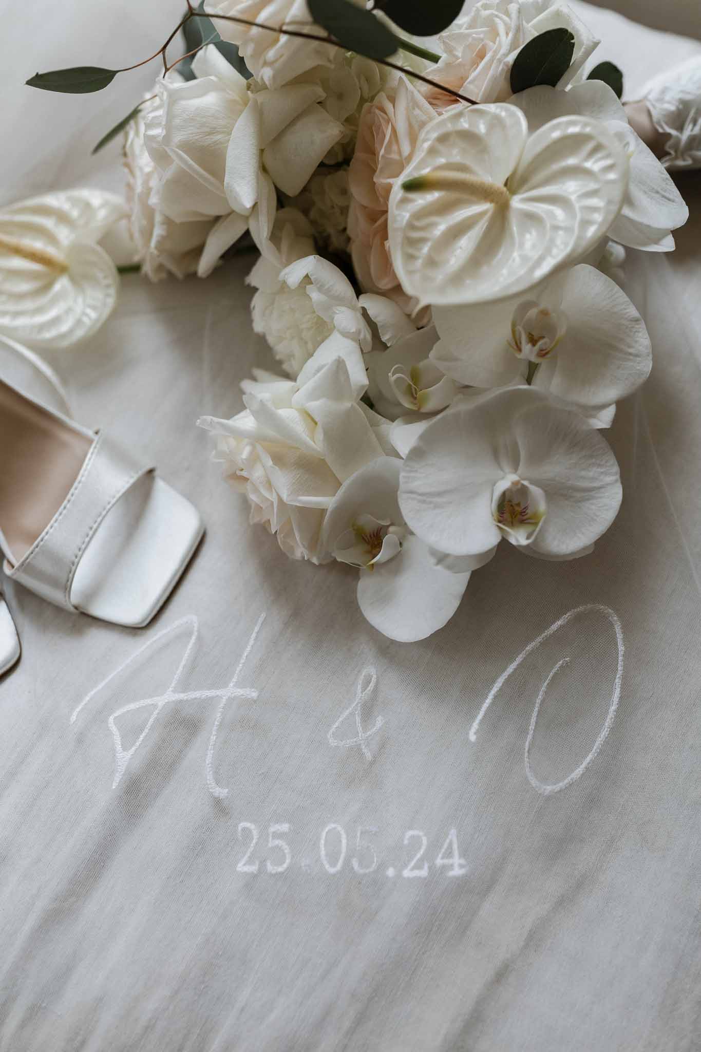 Bridal bouquet with white orchids and personalized embroidered wedding linens flat lay detail