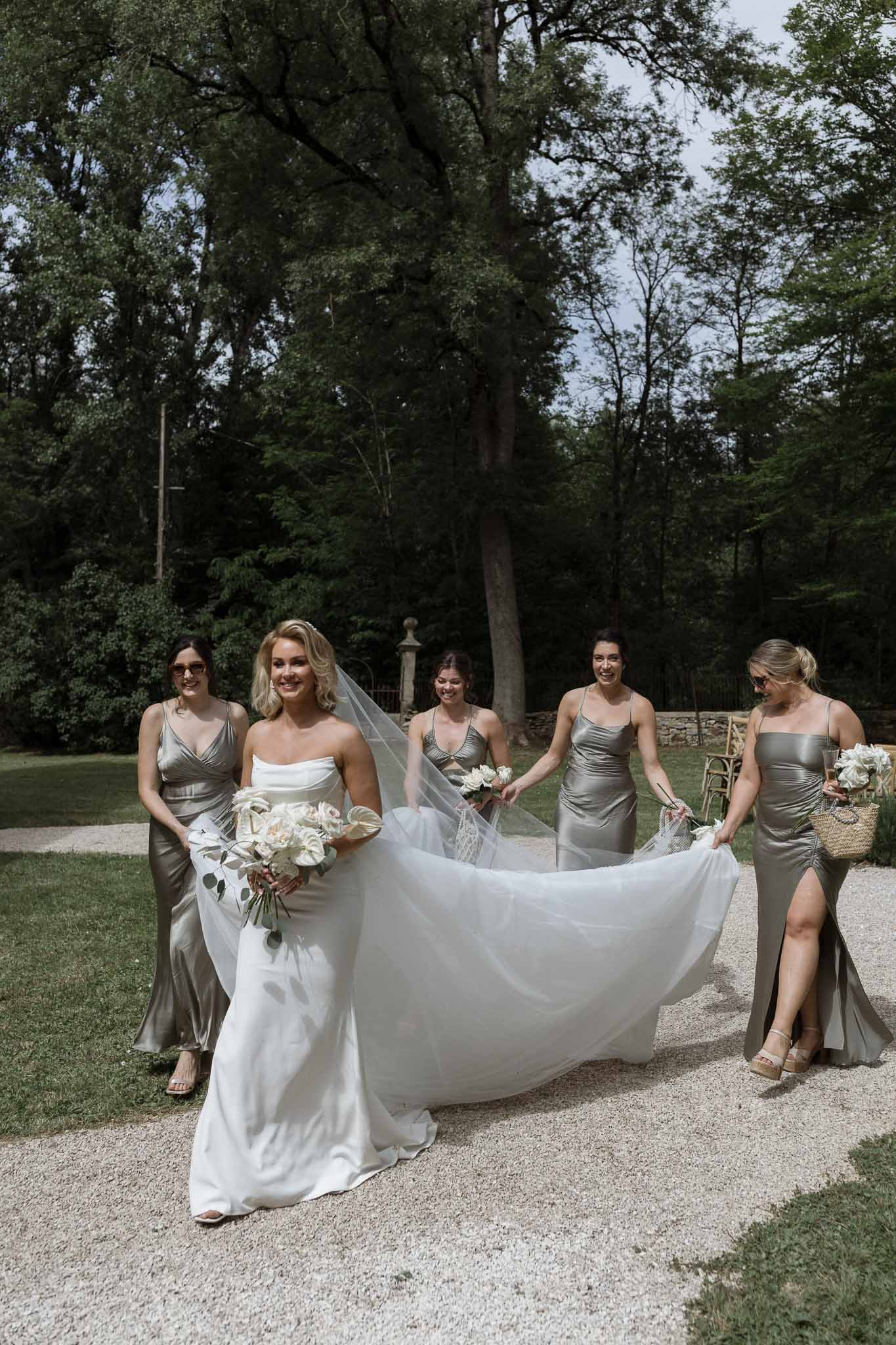 Bride with bridesmaids in sage dresses walking in garden setting