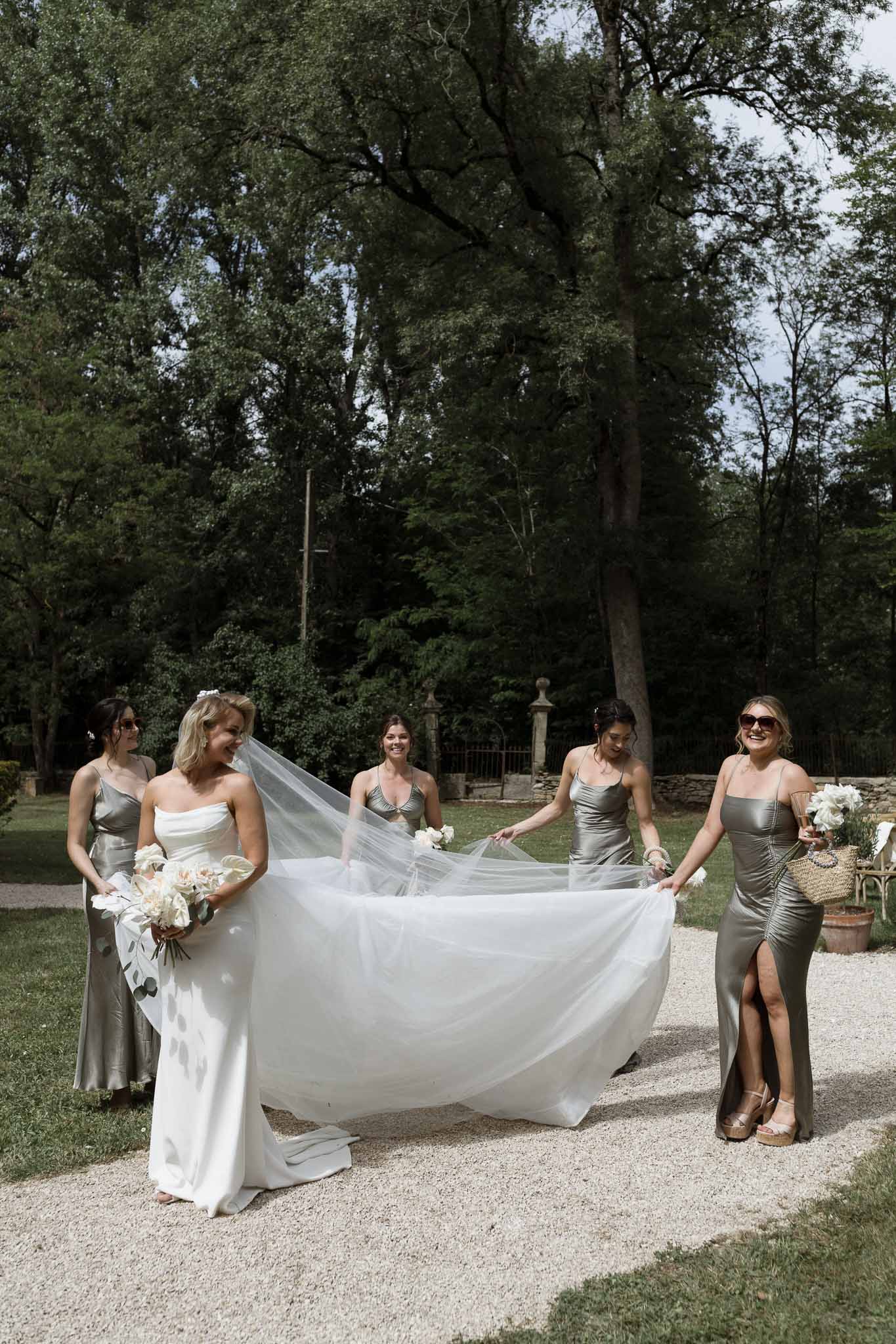 Bride and bridesmaids group portrait in formal garden with flowing veil