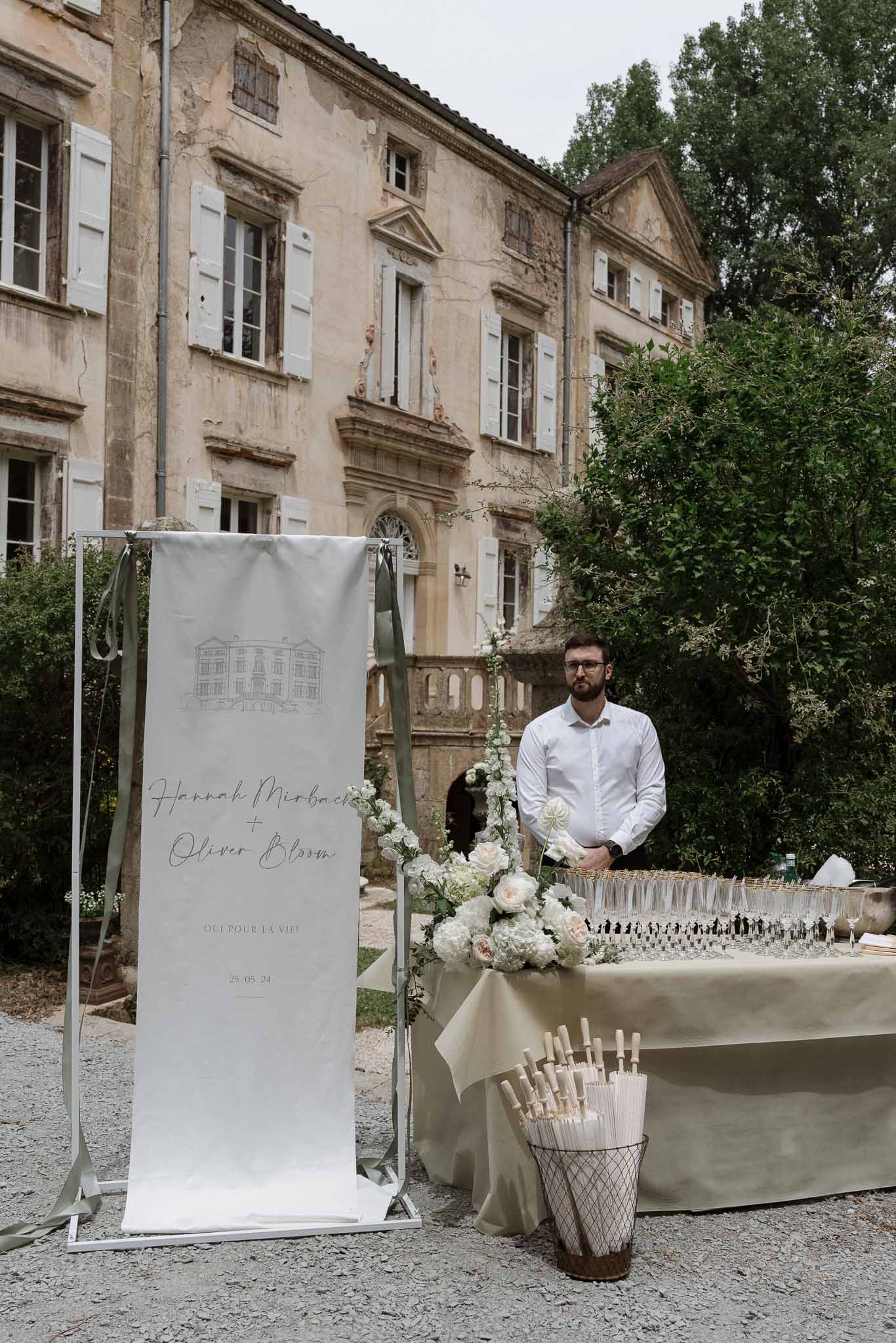 Cocktail hour setup with welcome station in stone château courtyard with ivy-covered facade