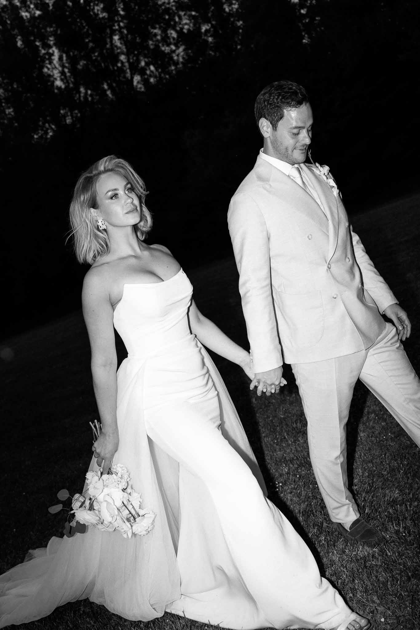 Bride and groom walking hand in hand during evening portrait session at garden venue