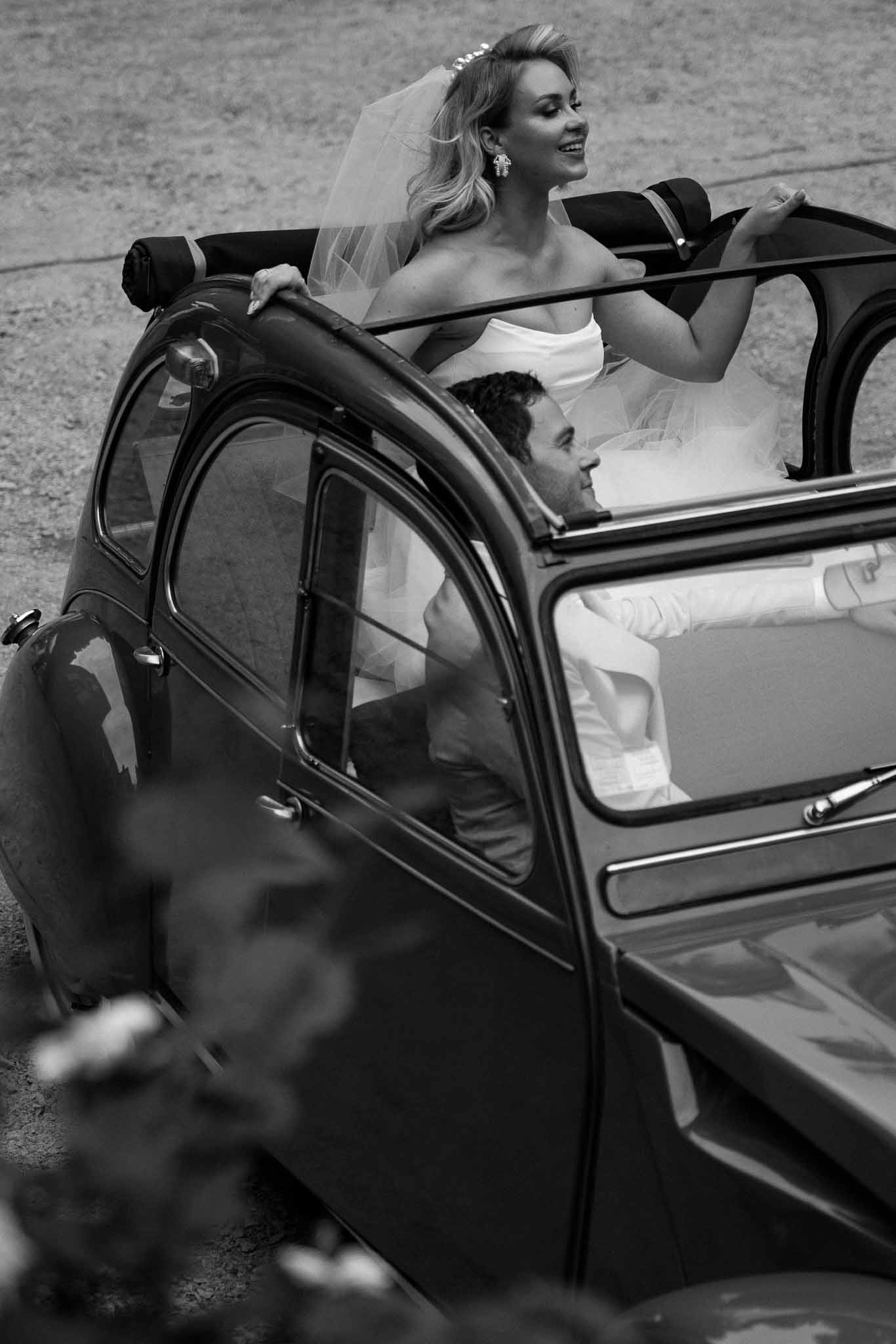 Bride and groom in vintage convertible car during wedding getaway