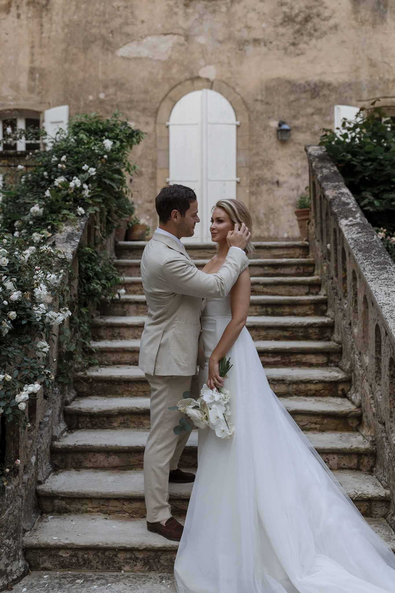 Bride and groom portrait on stone staircase at historic European-style courtyard wedding venue