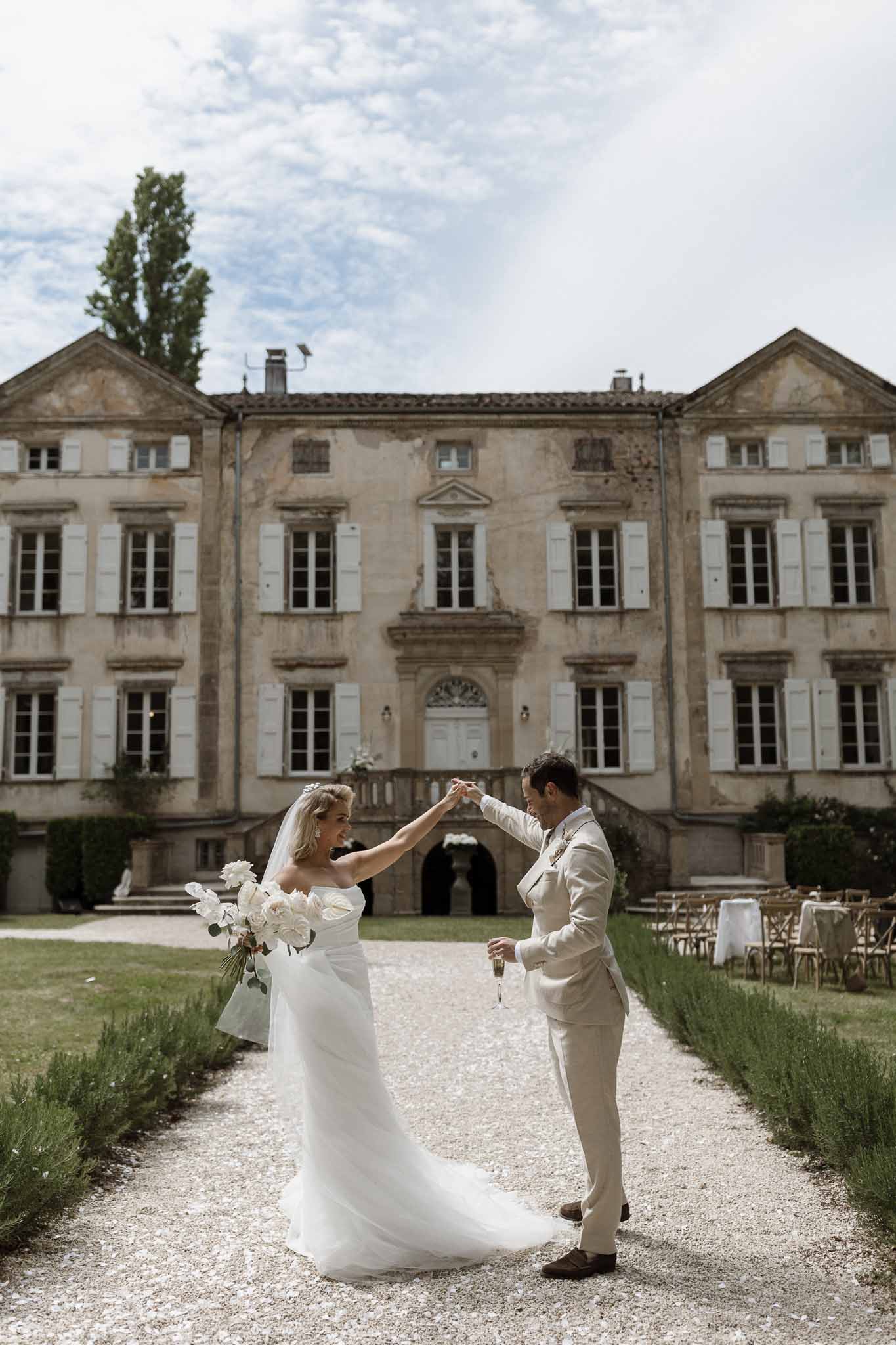 Bride and groom dancing in courtyard of Italian villa with lavender bushes and classical architecture